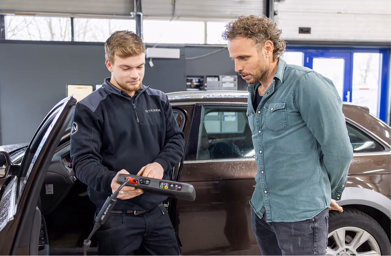 Een automonteur overlegt met de klant over de inhoud van een reparatie