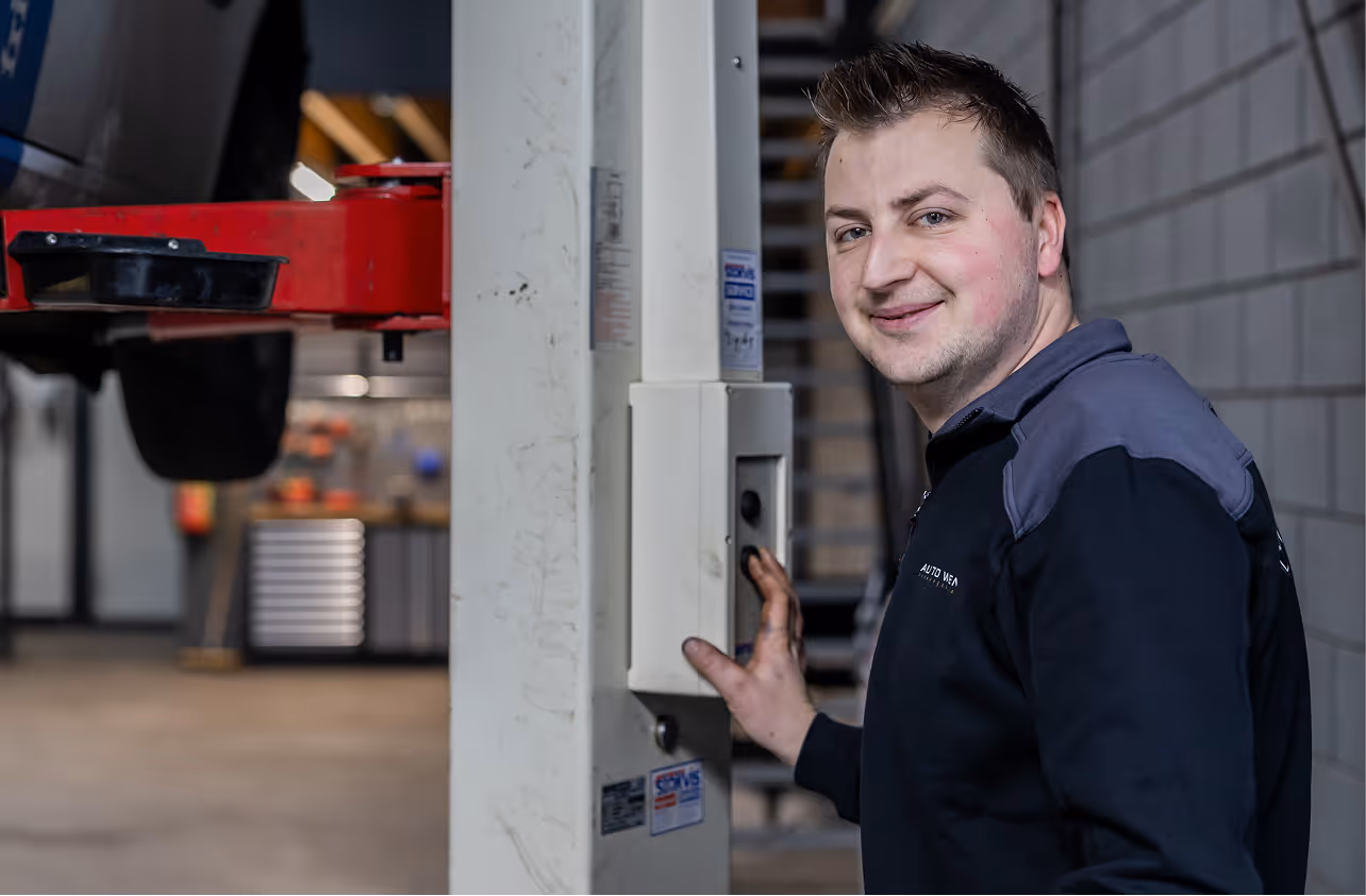 Een monteur drukt op de knoppen van een autobrug om deze te verlagen