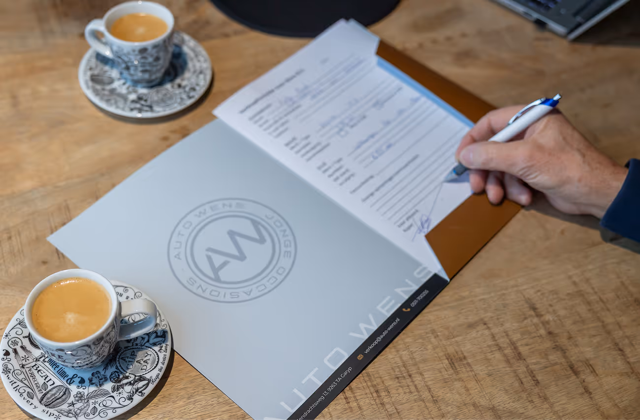 Het aankoopcontract inclusief inruil wordt ondertekend onder het genot van een bakje koffie bij Auto Wens