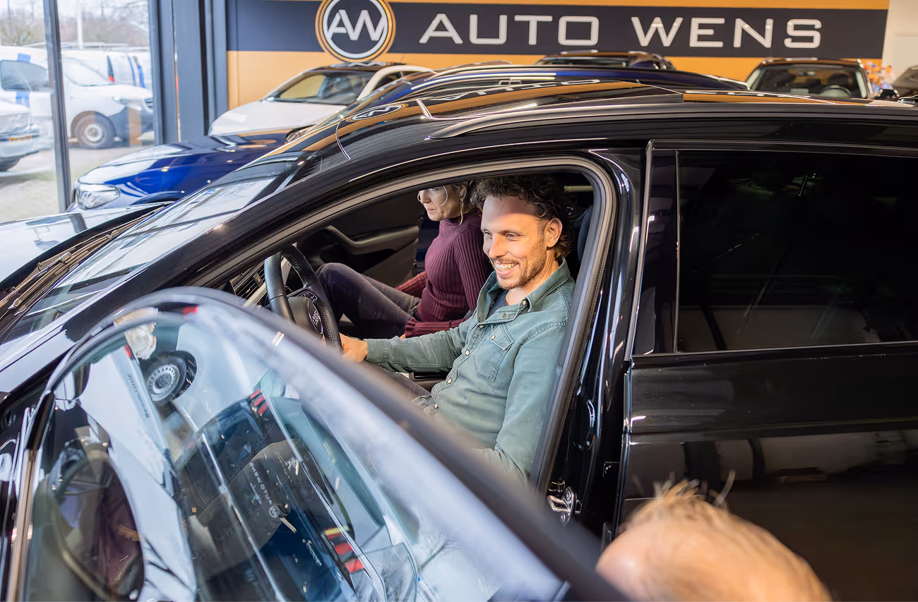 Een occasion wordt afgeleverd aan de klant in de showroom van Auto Wens