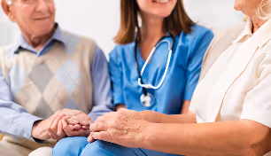 Healthcare professional holding hands with two elderly patients in a supportive gesture.