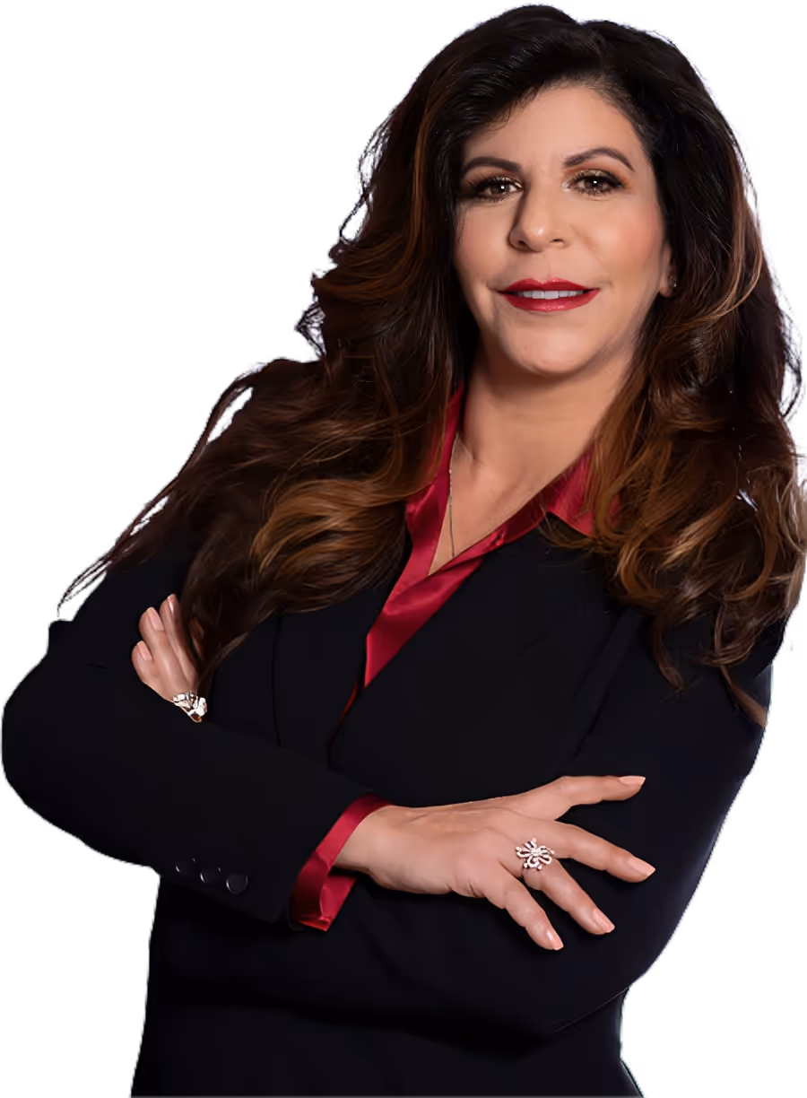 Confident woman with long wavy brown hair in a black blazer over a red blouse, arms crossed.