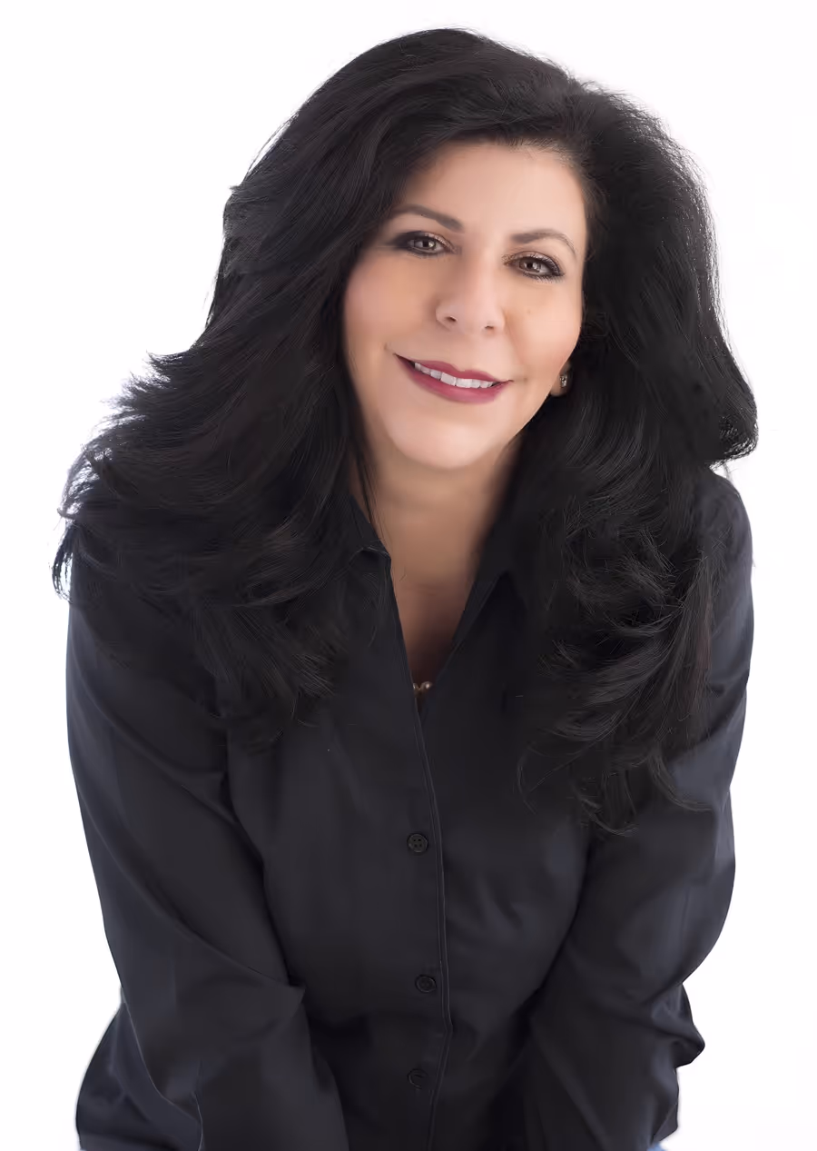 Smiling woman with long dark hair wearing a black button-up shirt against a white background.