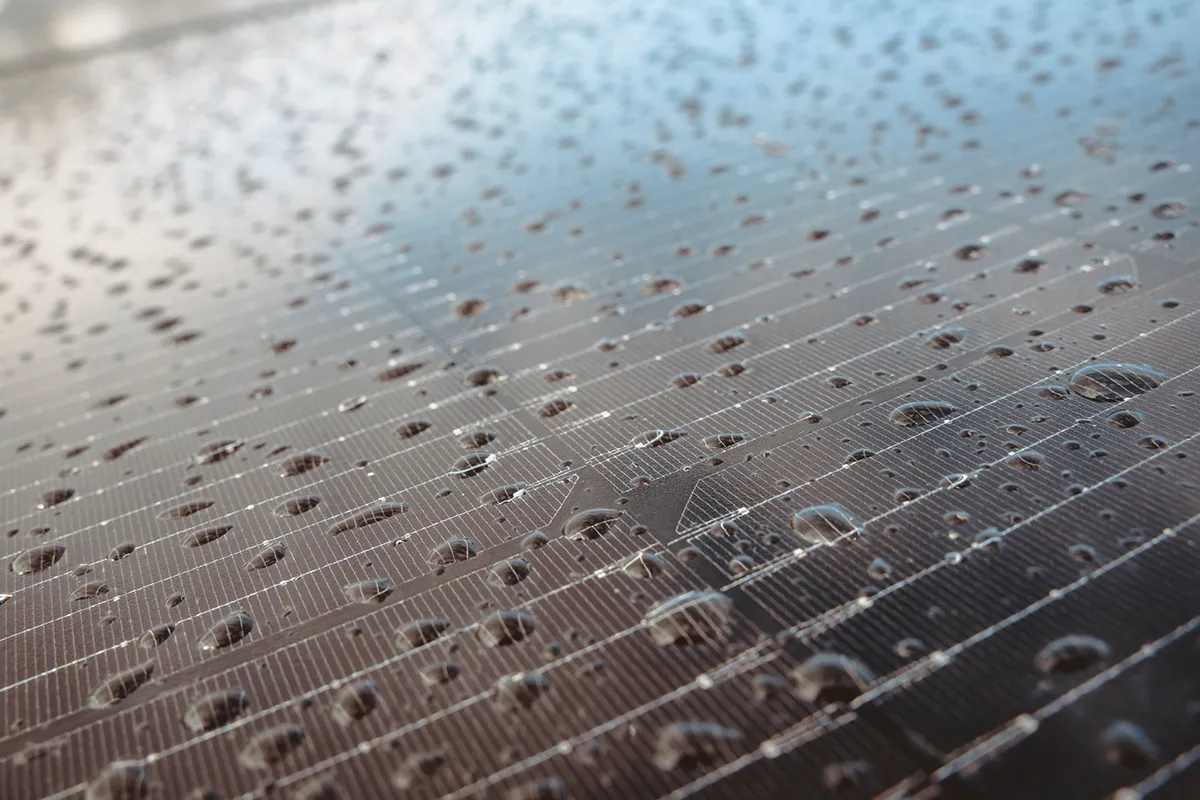 Detailaufnahme eines Solarmoduls mit Regentropfen.