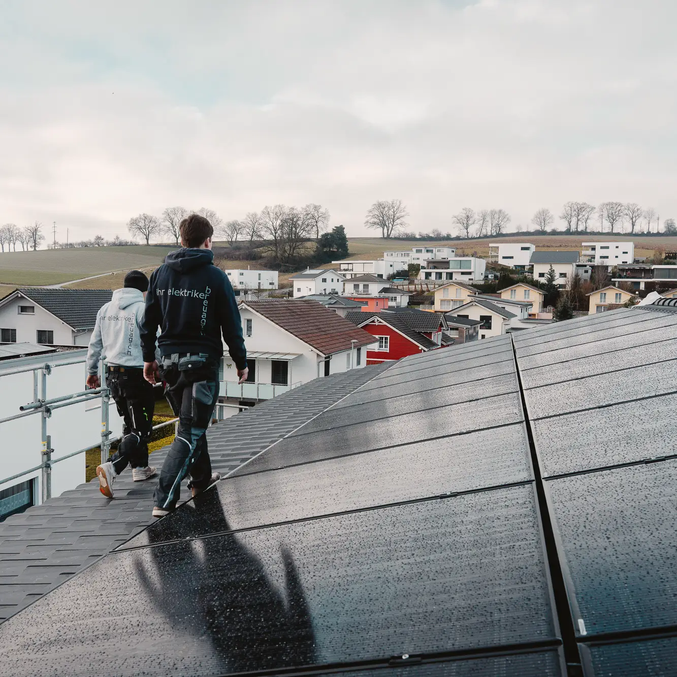 Zwei Monteure auf einem Dach mit Photovoltaikmodulen in Riggisberg.