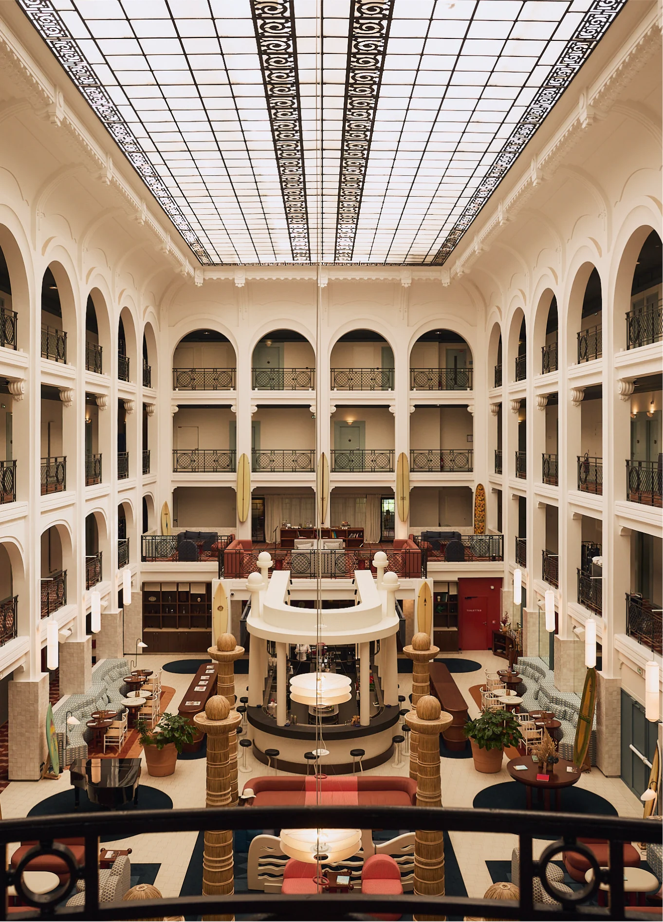 Panoramic view of the spectacular and bright atrium of the Regina Experimental hotel, featuring its classic arches and glass roof.
