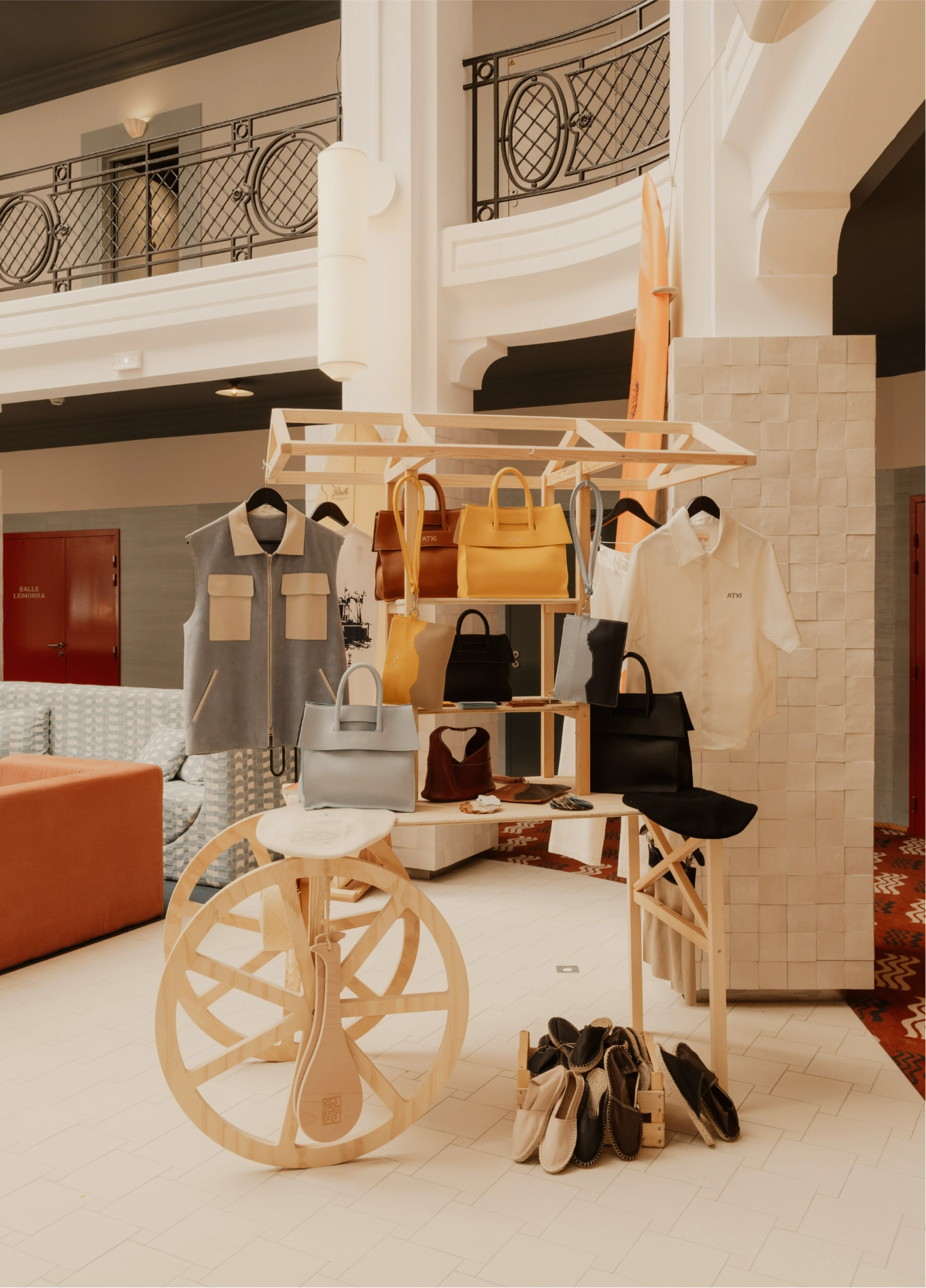 Creative decorative display in the shape of a cart wheel in a retail space, highlighting handbags, accessories, and leather goods.