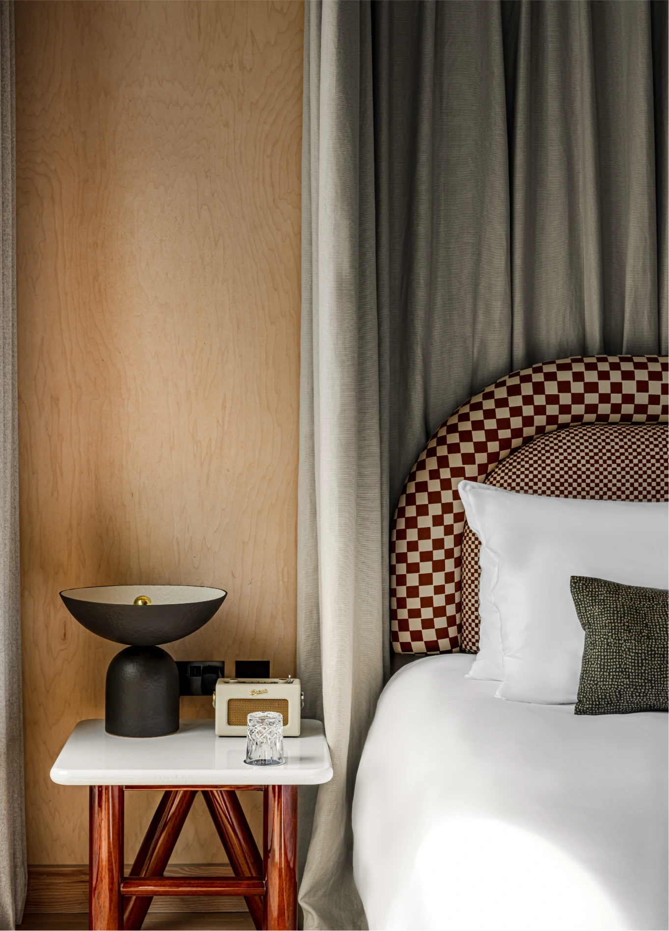 Bedroom with white linen bed and rattan bedside table at Cowley Manor Experimental, Cotswolds