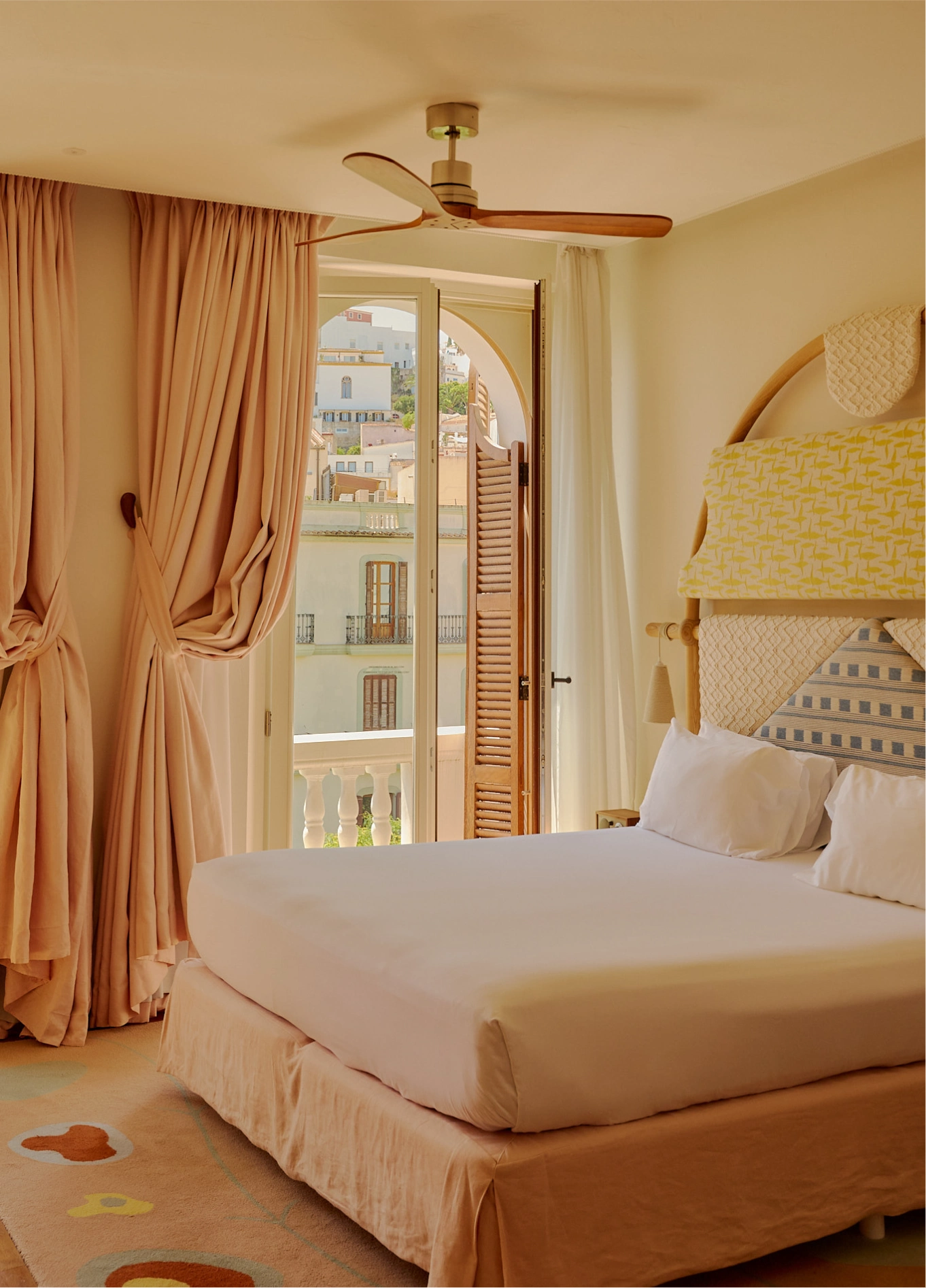 Elegant and bright bedroom at Experimental Beach Ibiza, featuring a large comfortable bed, beige curtains, and a French door leading outside.