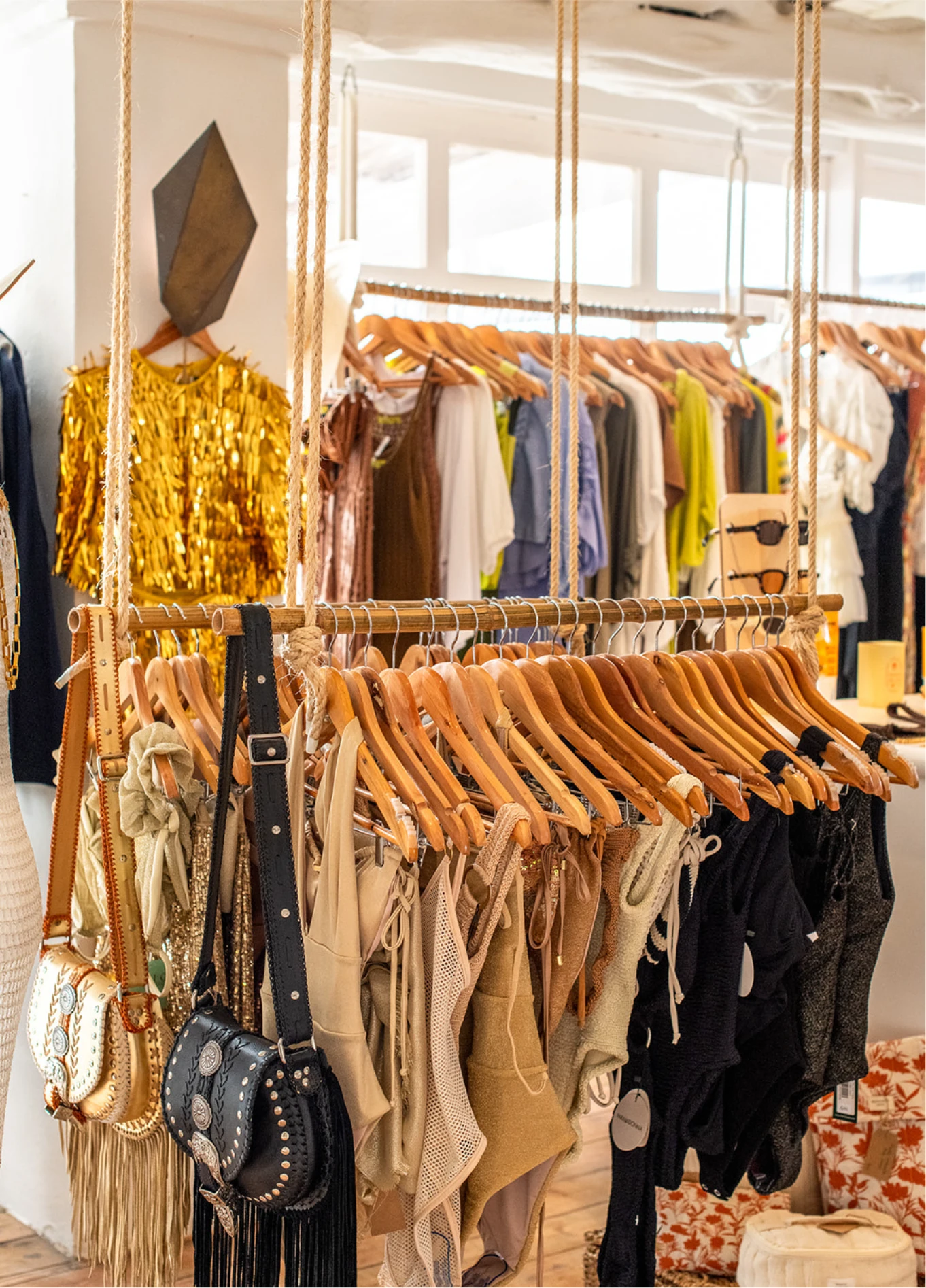 Clothing store display rack with hangers loaded with various items and a hanging handbag.