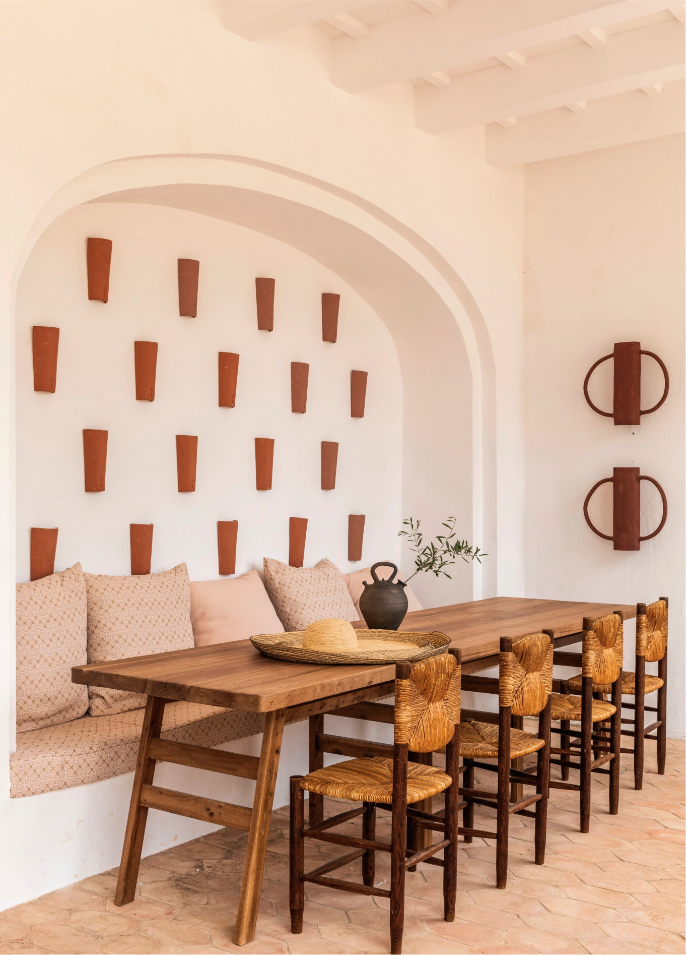 Overview of the dining space at Manorca Experimental, combining rustic design, comfortable banquettes, and artisanal wall decorations under an arch.