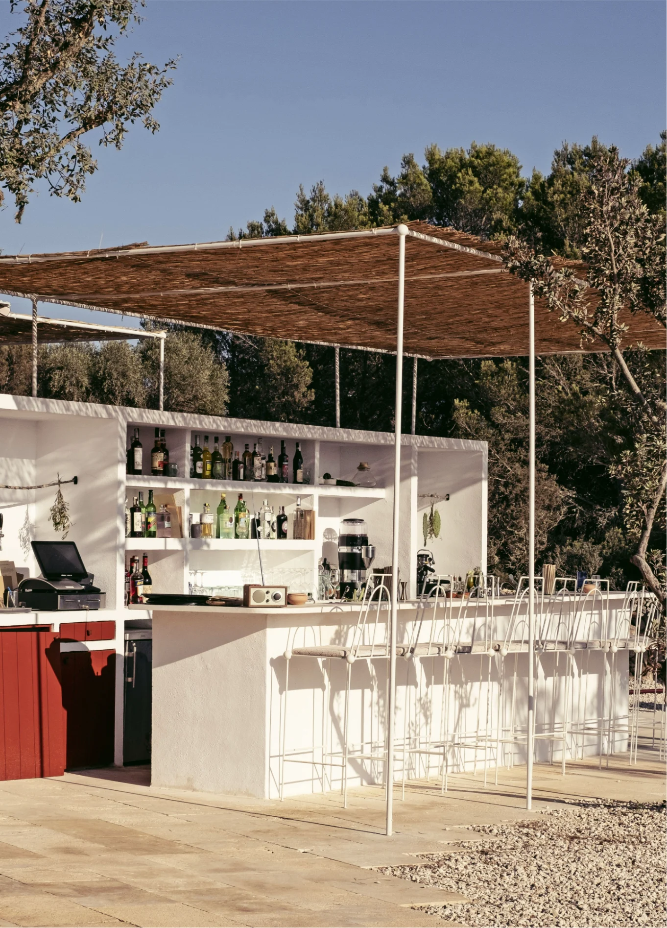 Modern and elegant outdoor beach bar, featuring a clean white structure under a wooden pergola, offering a relaxed atmosphere.