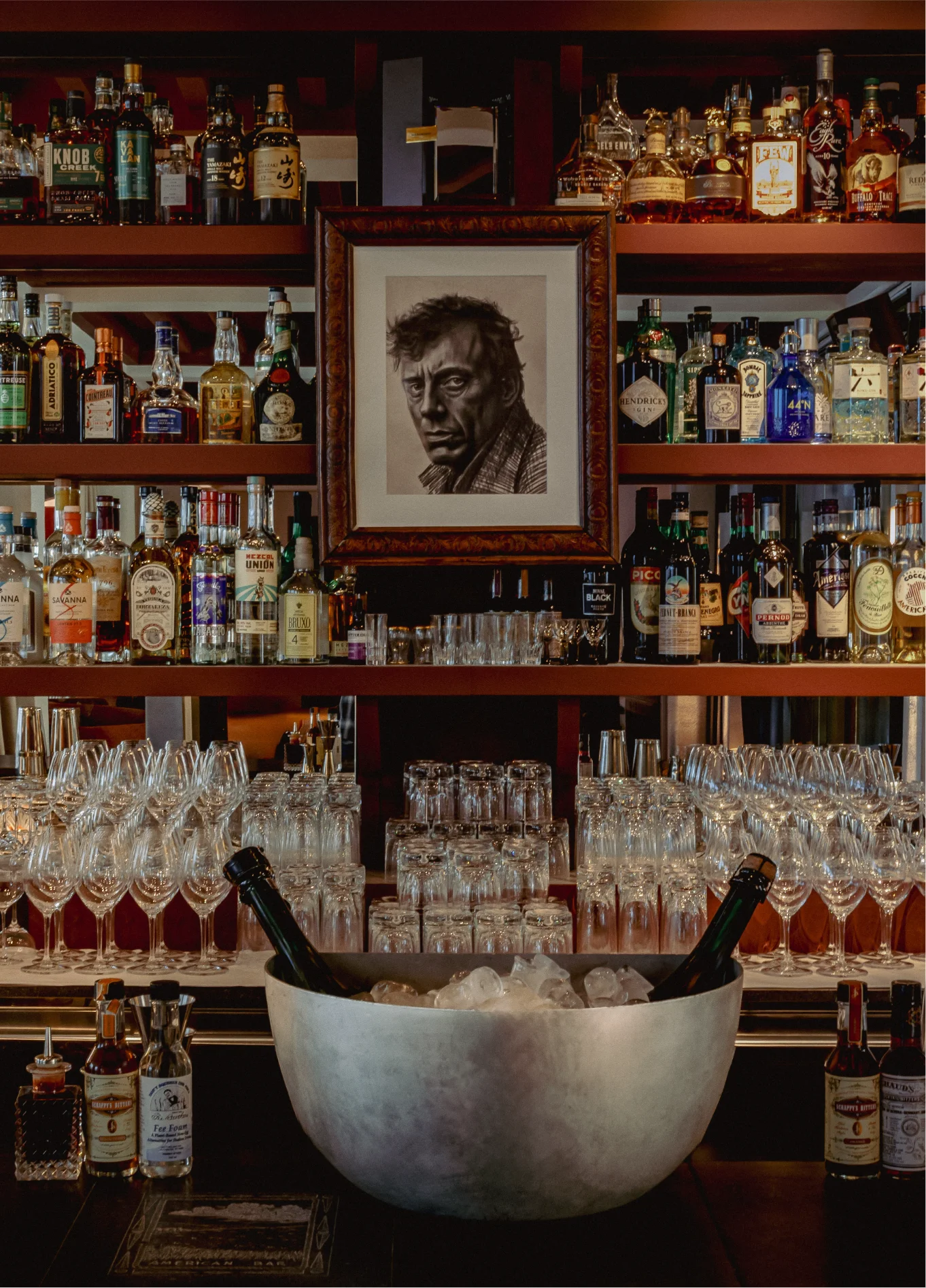 Wall of bottles with portrait and ice bucket at American Bar, Experimental Marais, Paris