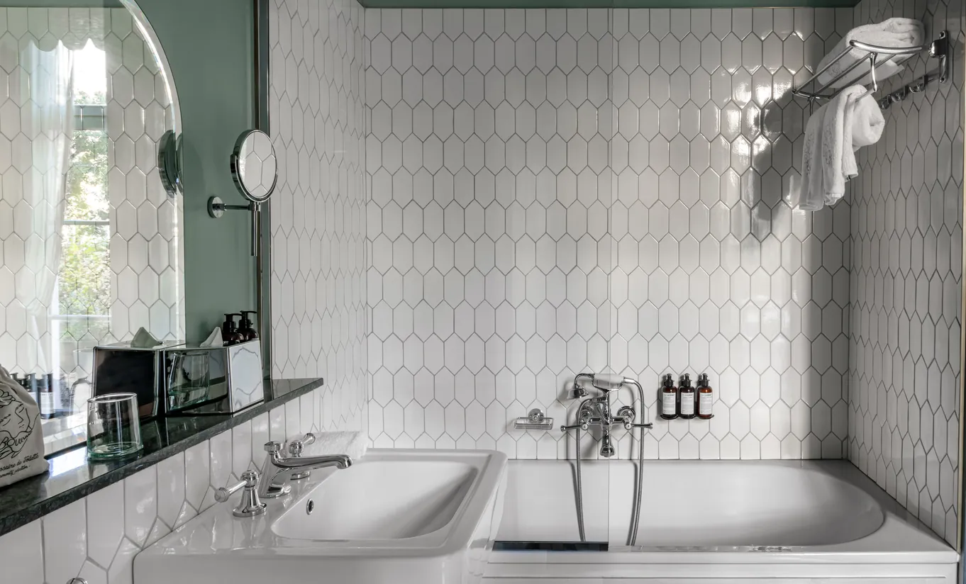 Salle de bain avec double vasque, carrelage métro blanc et miroir rond dans la chambre Grand Boulevard de Grands Boulevards Experimental, hôtel boutique proche de l'Opéra Garnier, Paris 2e