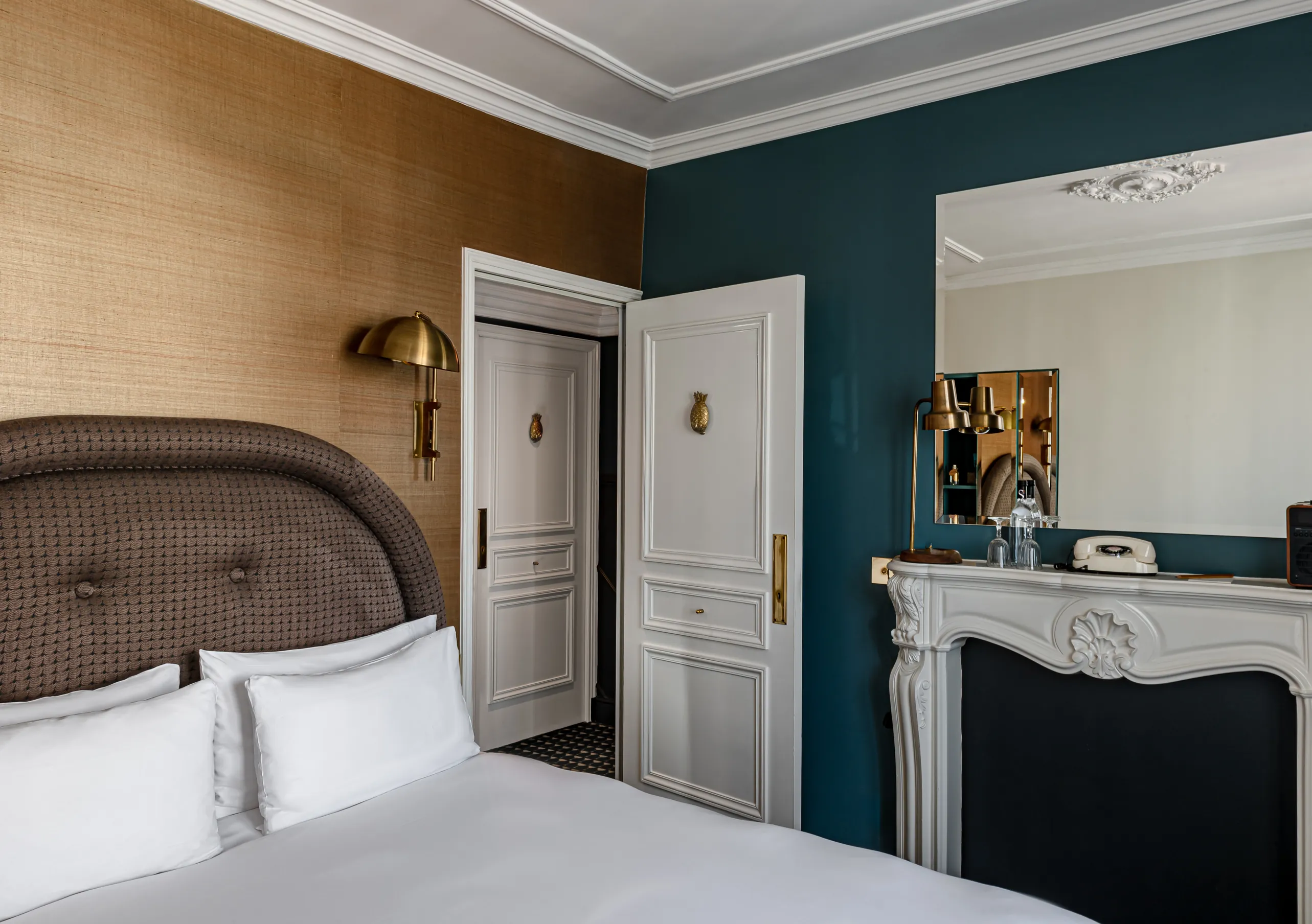 Chambre avec grand lit blanc, tête de lit tressée, cheminée blanche et murs bleu canard dans la chambre Sopi Balcon de Grand Pigalle Experimental, hôtel boutique dans le 9e arrondissement de Paris, Pigalle