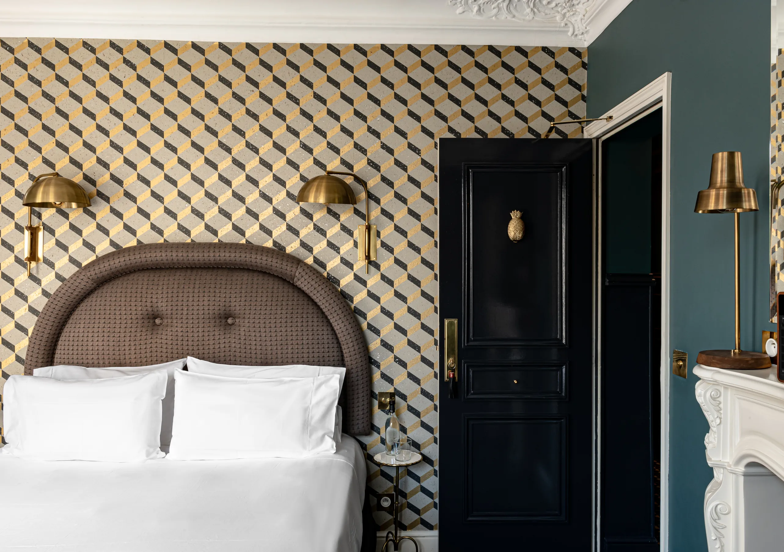 Chambre avec grand lit blanc, tête de lit tressée, murs à motifs géométriques et appliques dorées dans la chambre Pigalle de Grand Pigalle Experimental, hôtel boutique dans le 9e arrondissement de Paris
