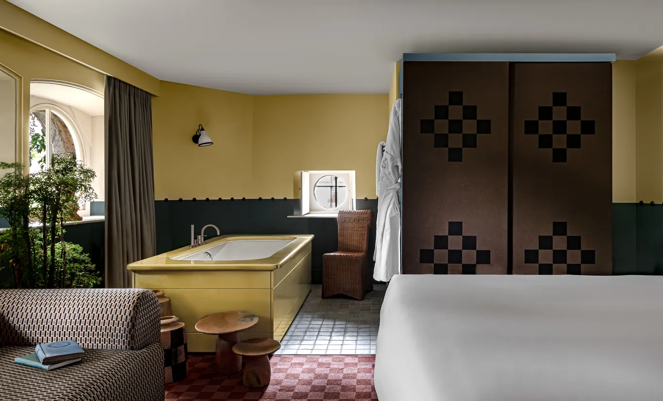 Salle de bain avec baignoire îlot, carrelage bordeaux et fenêtre en arche dans la chambre Wildflower de Cowley Manor Experimental, Cotswolds