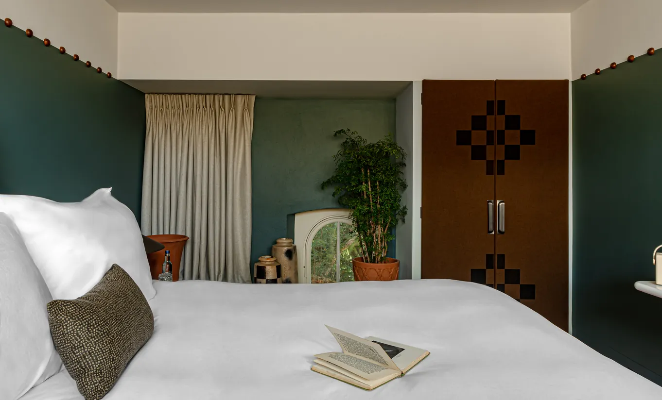 Chambre avec grand lit blanc, murs bleu canard et porte en bois dans la chambre Treehouse de Cowley Manor Experimental, Cotswolds