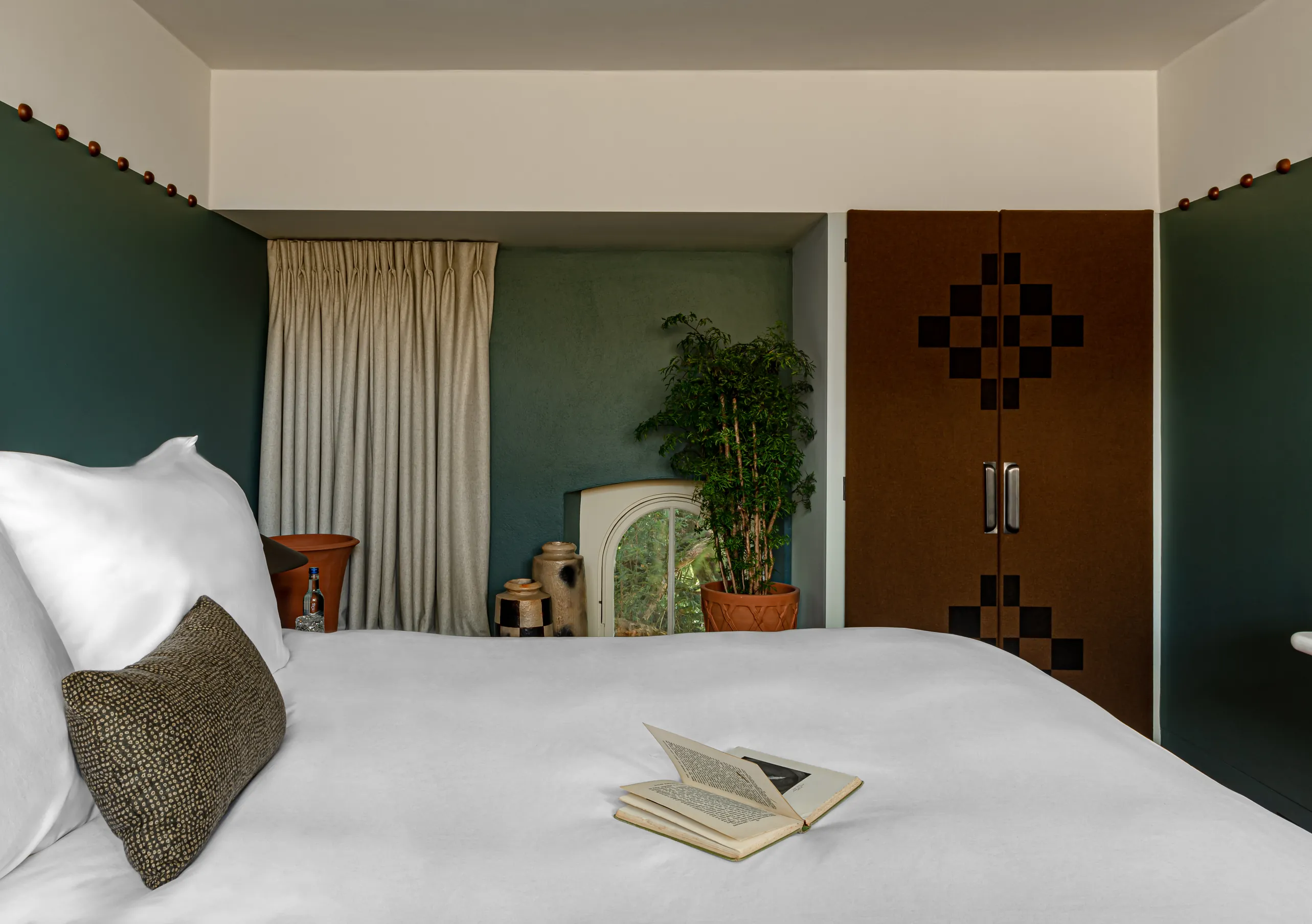 Chambre avec grand lit blanc, murs bleu canard et porte en bois dans la chambre Treehouse de Cowley Manor Experimental, Cotswolds