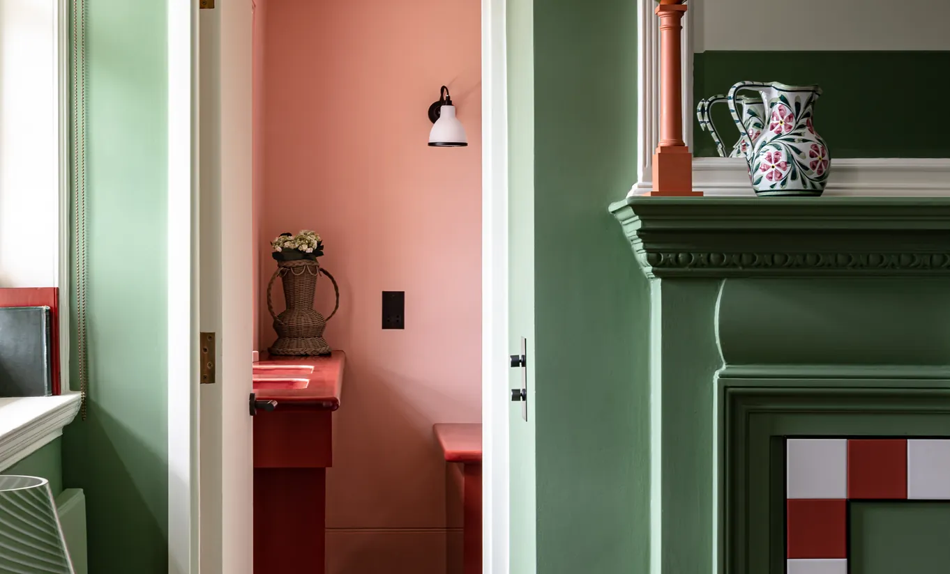 Détail d'un coin chambre avec boiseries vert sauge, cheminée en carrelage rouge et blanc et murs terracotta dans la chambre Petite Cowley de Cowley Manor Experimental, Cotswolds