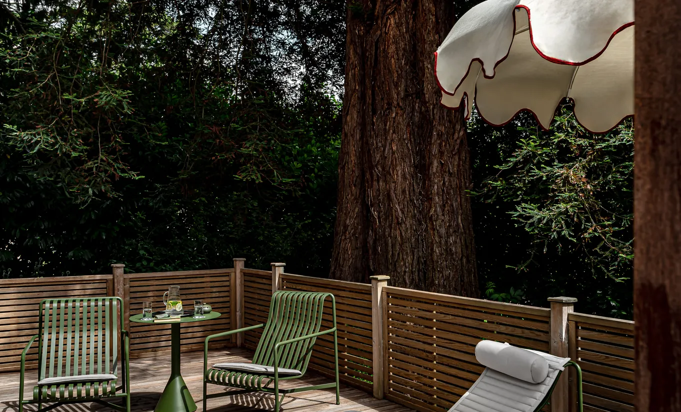 Terrasse privée en bois avec chaises de jardin entourées de grands arbres dans la chambre Wildflower avec terrasse de Cowley Manor Experimental, idéal pour une escapade relaxante à la campagne dans les Cotswolds