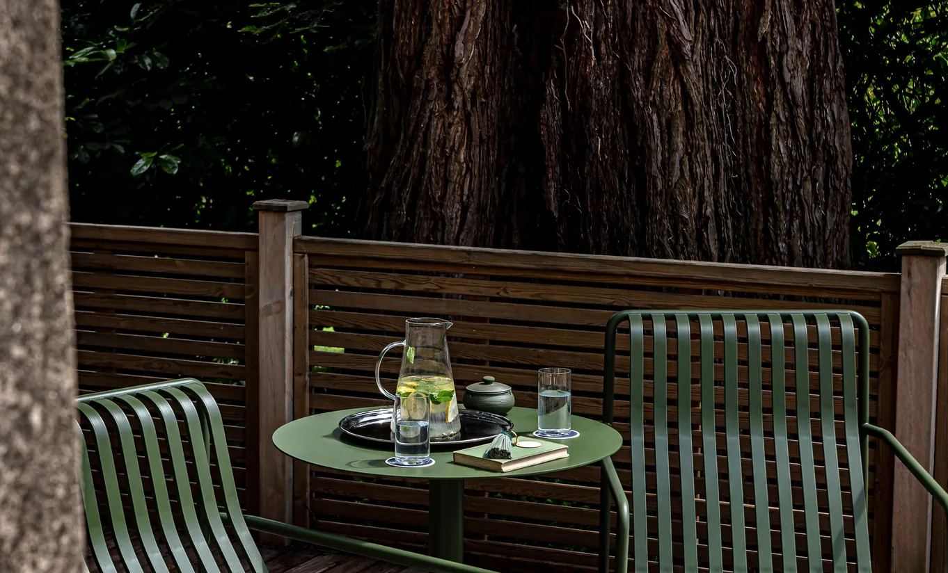 Terrasse privée en bois avec petite table dressée pour un verre entourée d'arbres à Cowley Manor Experimental, idéal pour un moment calme dans la campagne des Cotswolds