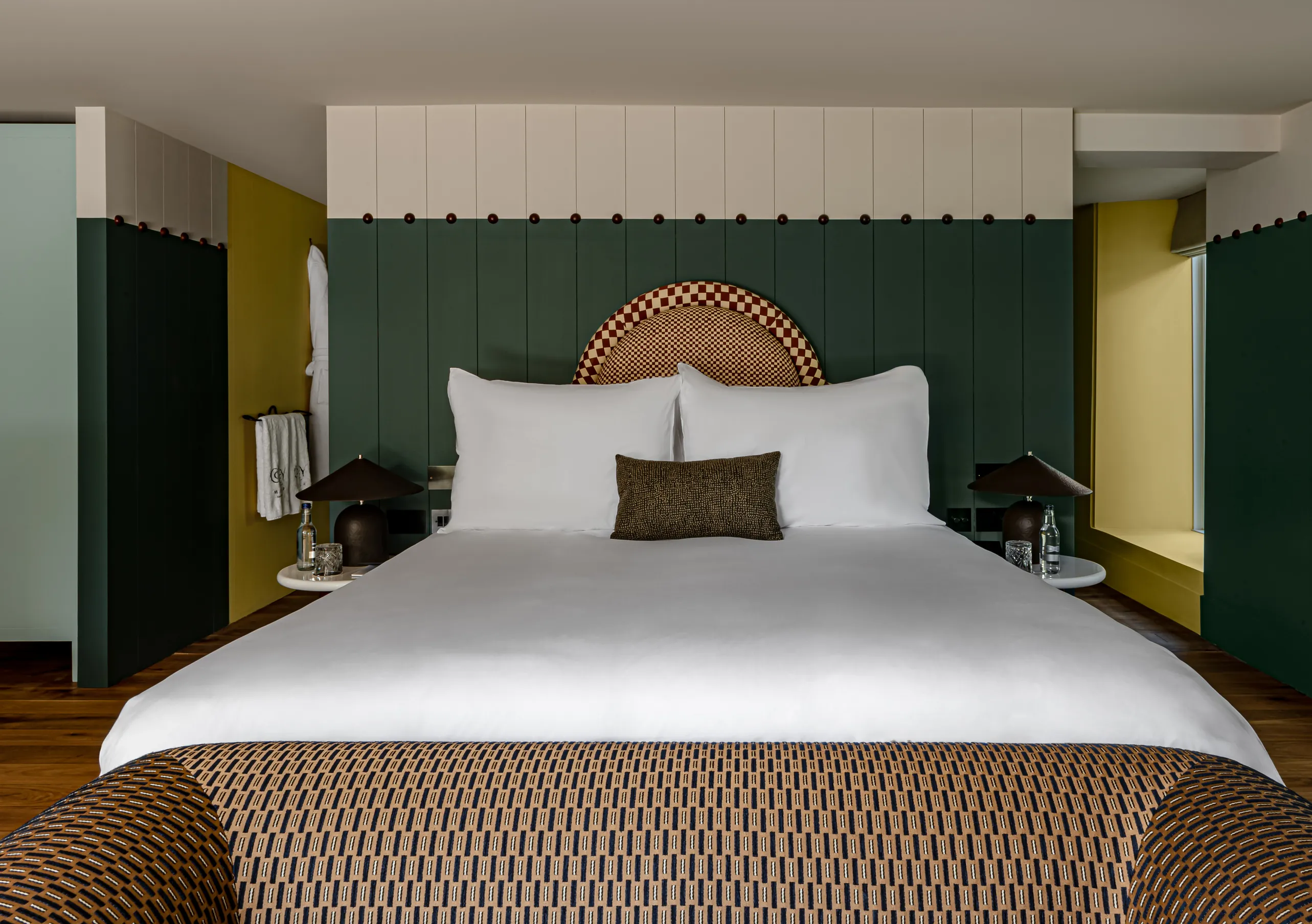 Chambre avec lit king-size, murs jaune moutarde, boiseries vert foncé et tête de lit en rotin dans la chambre Wildflower avec terrasse de Cowley Manor Experimental, Cotswolds
