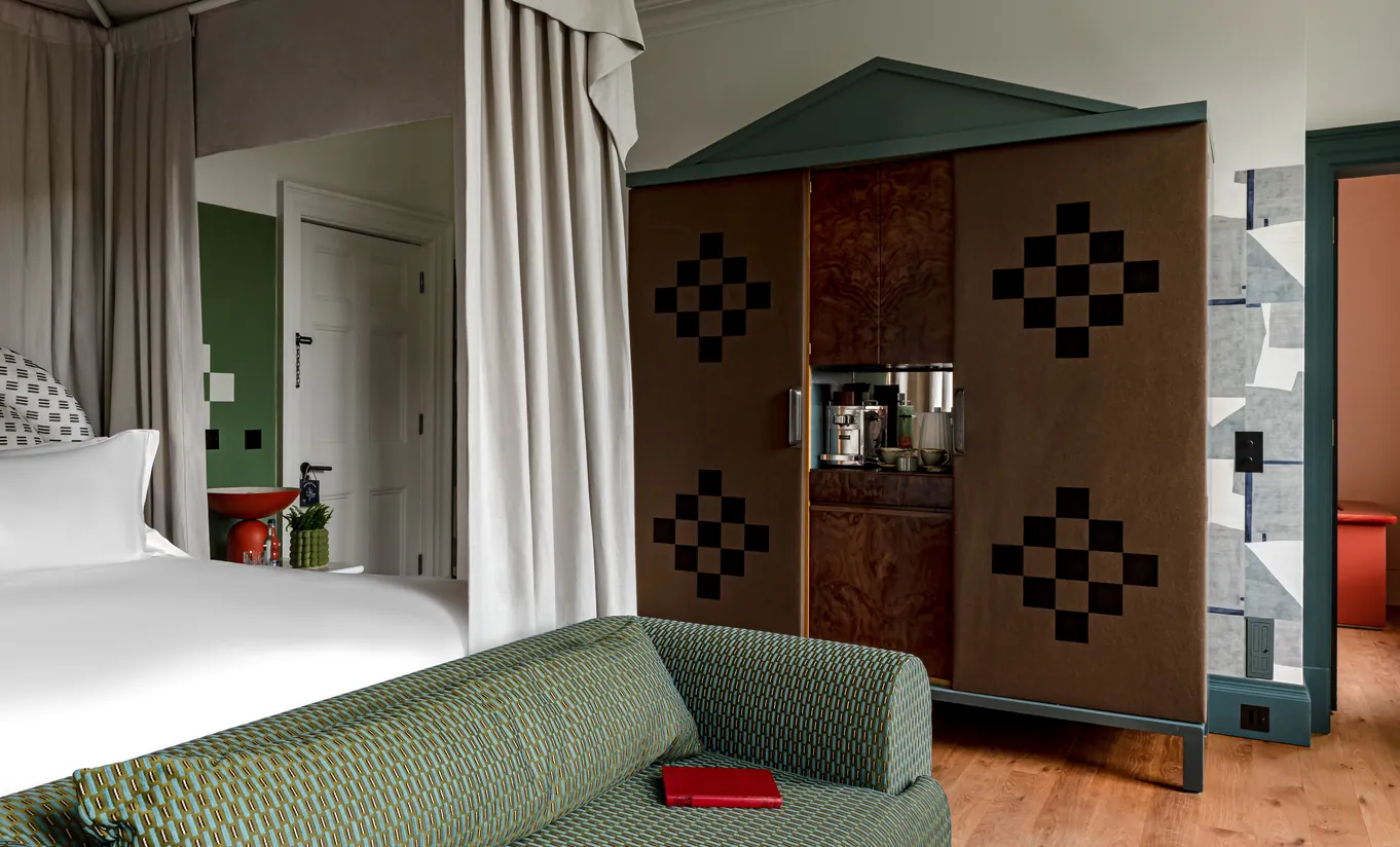 Chambre avec grand lit blanc, armoire à motifs damier et rideaux au sol dans la chambre Water Lily de Cowley Manor Experimental, retraite à la campagne dans les Cotswolds