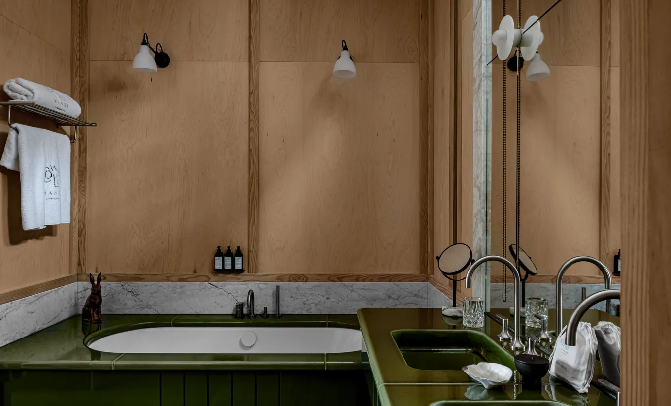 Salle de bain avec baignoire encastrée verte, murs en pierre et robinetterie vintage dorée dans la chambre Waterlily with Terrace de Cowley Manor Experimental, hôtel spa de luxe dans les Cotswolds