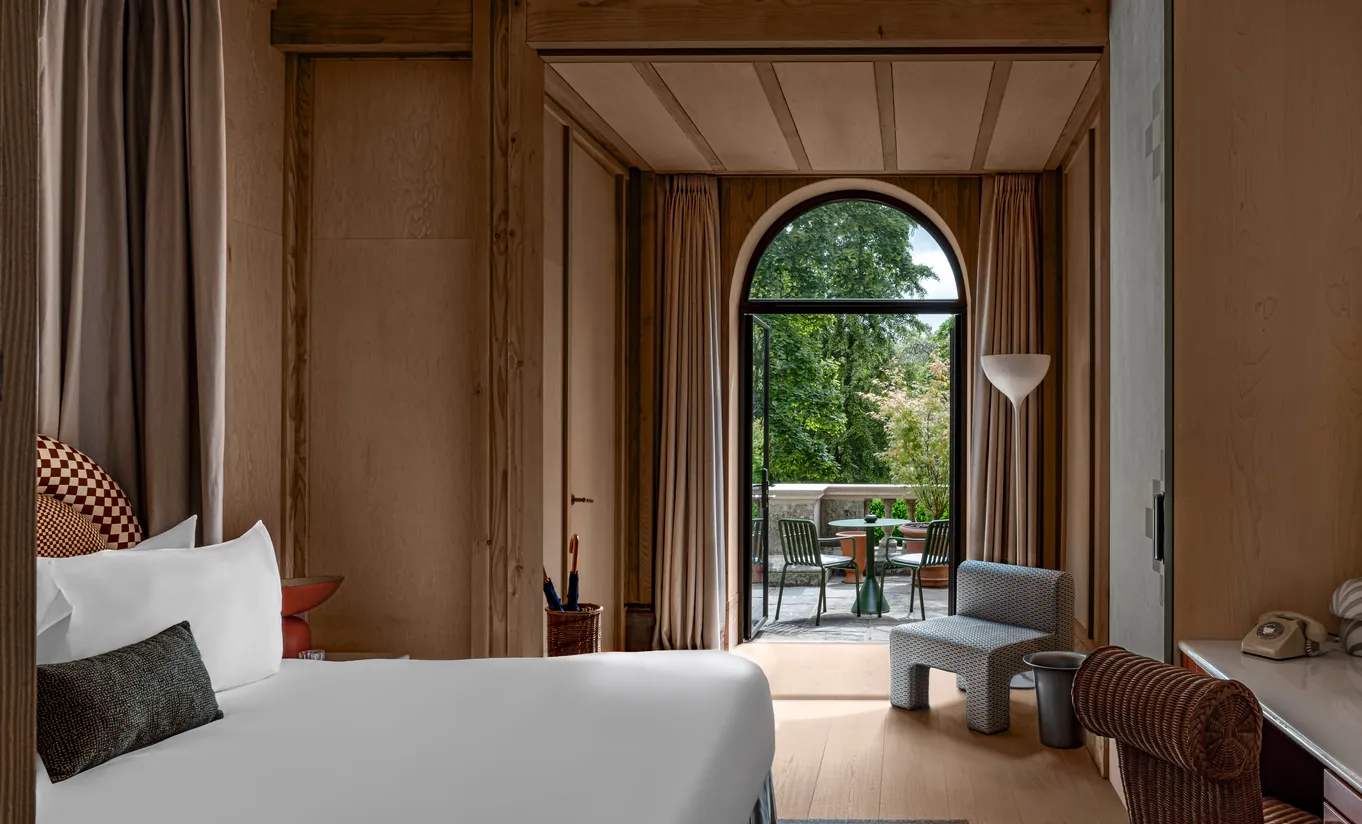 Chambre avec grand lit blanc et porte en arche ouvrant sur une terrasse privée avec vue sur le jardin dans la chambre Waterlily with Terrace de Cowley Manor Experimental, Cotswolds