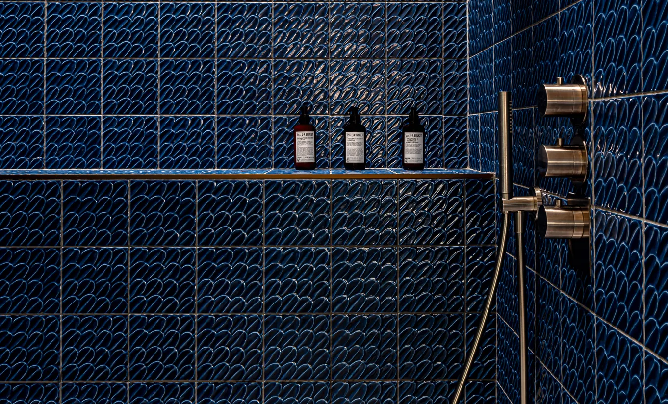 Douche à l'italienne avec carrelage mosaïque bleu marine et robinetterie dorée dans la Churns River Junior Suite de Cowley Manor Experimental, Cotswolds
