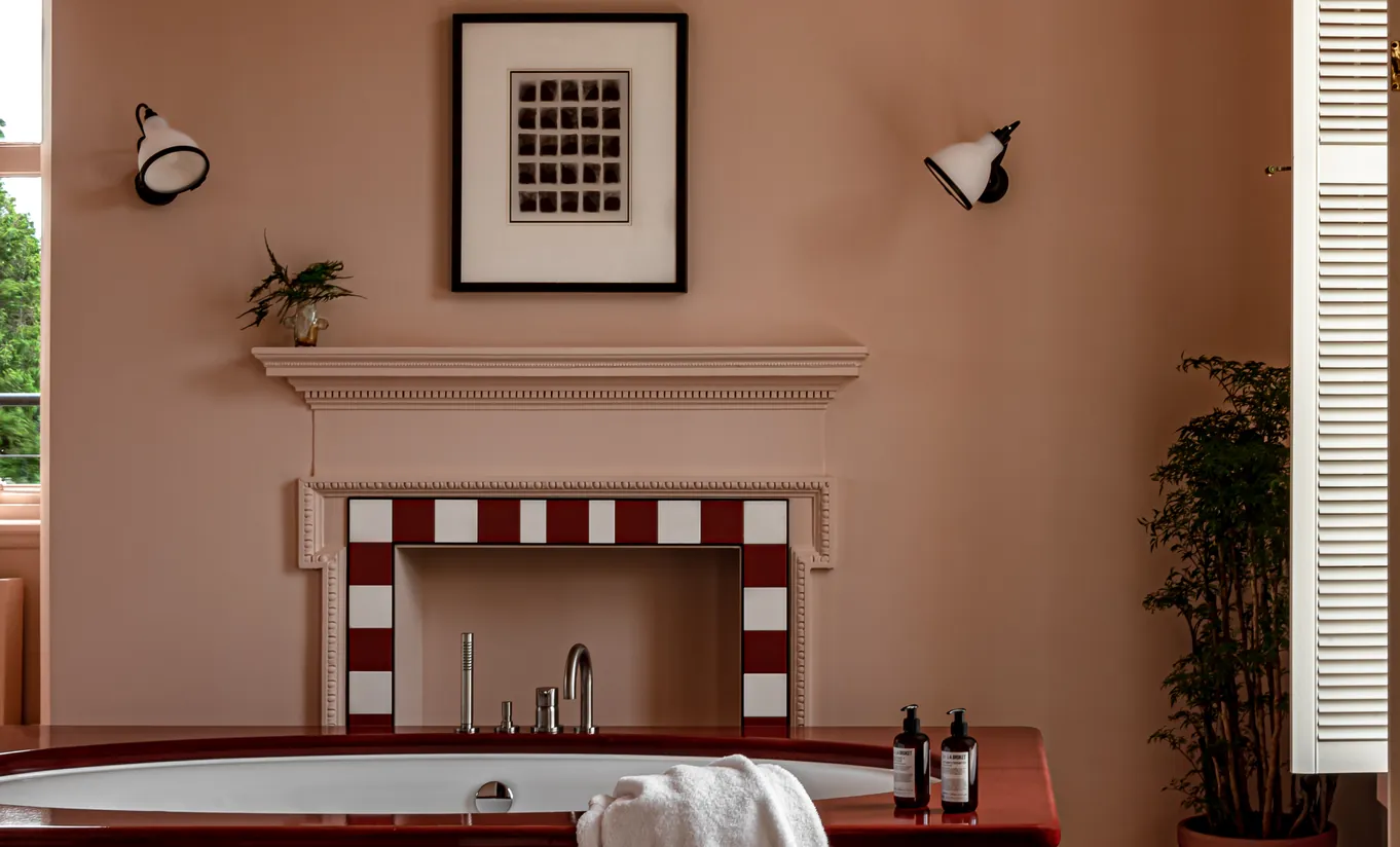 Salle de bain avec cheminée en carrelage rouge et blanc, murs terracotta et baignoire îlot dans la Cowley Manor Suite de Cowley Manor Experimental, Cotswolds