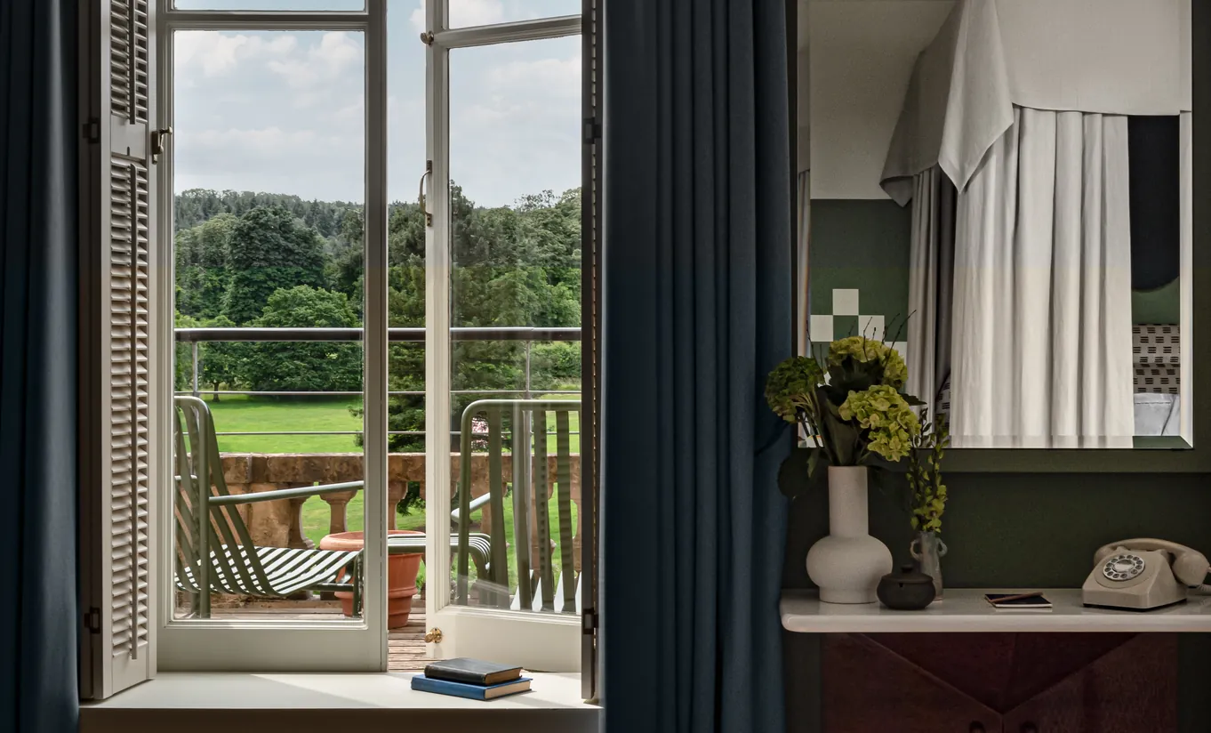 Balcon avec portes-fenêtres ouvertes donnant sur la campagne verdoyante des Cotswolds dans la Cowley Manor Suite de Cowley Manor Experimental, idéal pour un séjour romantique