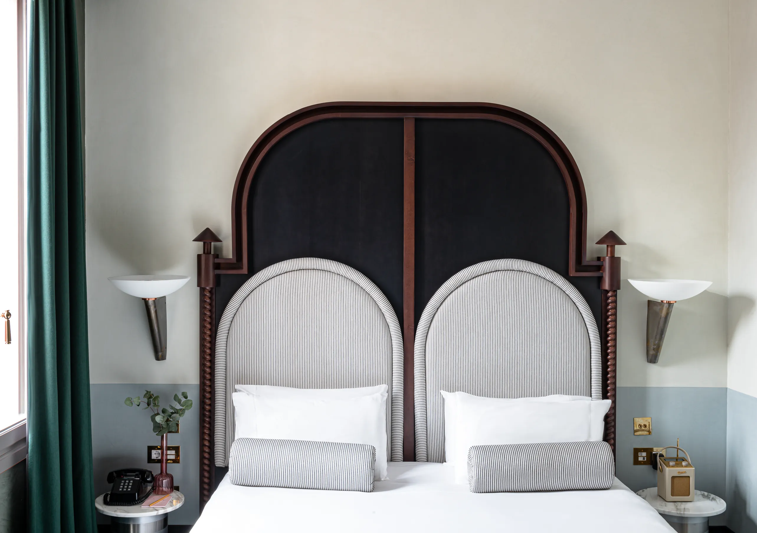 Il Palazzo Experimental twin bedroom with black arched headboard surround, paired wall sconces and teal curtains in Venice.