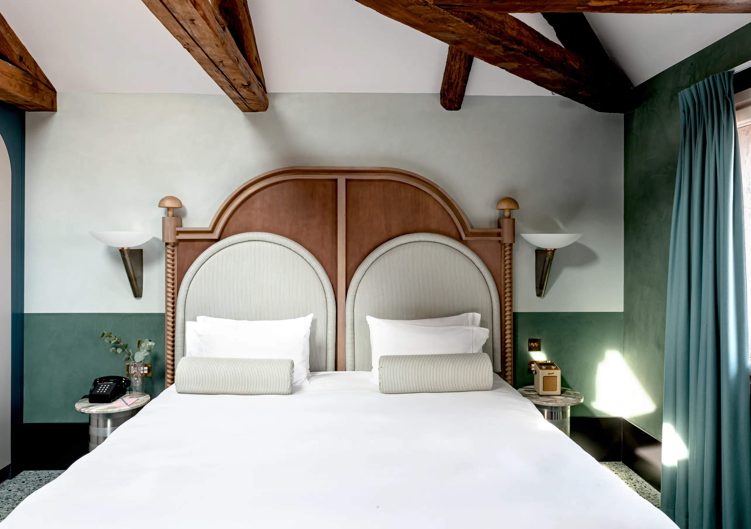 Il Palazzo Experimental double bedroom with walnut arched headboard, symmetrical sconces and exposed beams in Venice