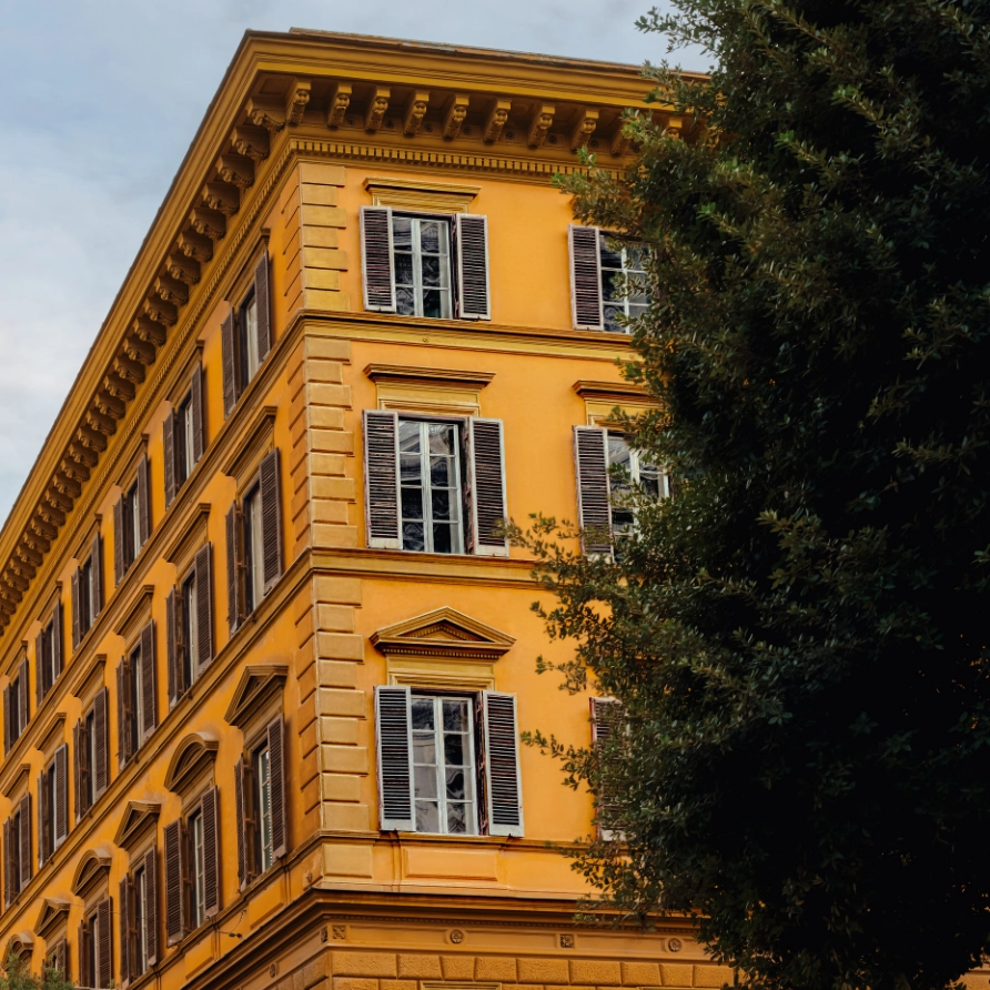 Ochre Roman building facade with shutters and cypress tree, Experimental Roma, Rome city center