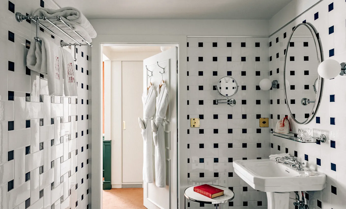 Bathroom with geometric black and white tiled walls, a shower and pedestal sink in the Classic Room at Experimental Chalet Verbier