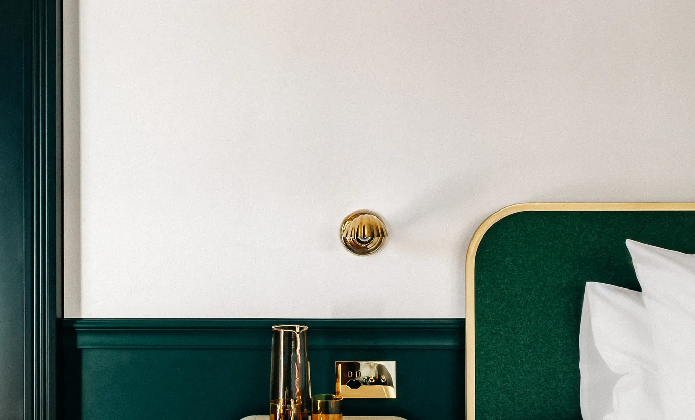 Close-up of a white pillow against a dark green velvet headboard in the Superior Room at Experimental Chalet Verbier