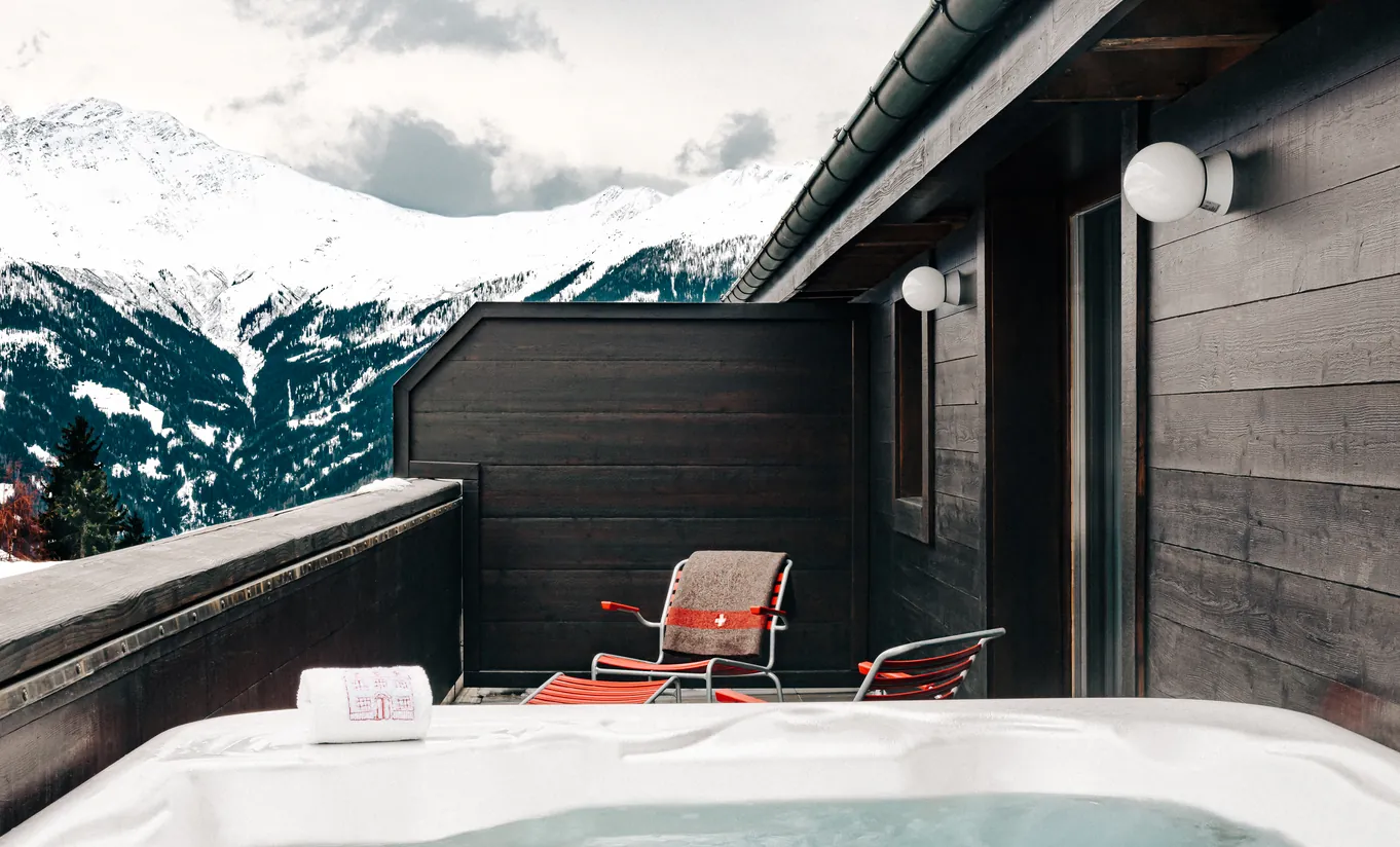 Private outdoor jacuzzi with a snowy mountain view in the Verbier Suite at Experimental Chalet Verbier, luxury ski and spa hotel in Verbier