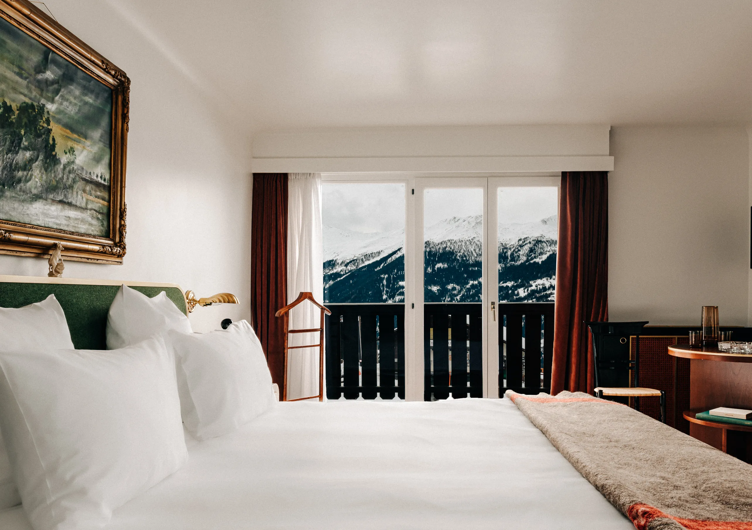 Bedroom with two single beds, olive green headboard and a view of the snowy Alps through the window in the Superior Room Terrace at Experimental Chalet Verbier