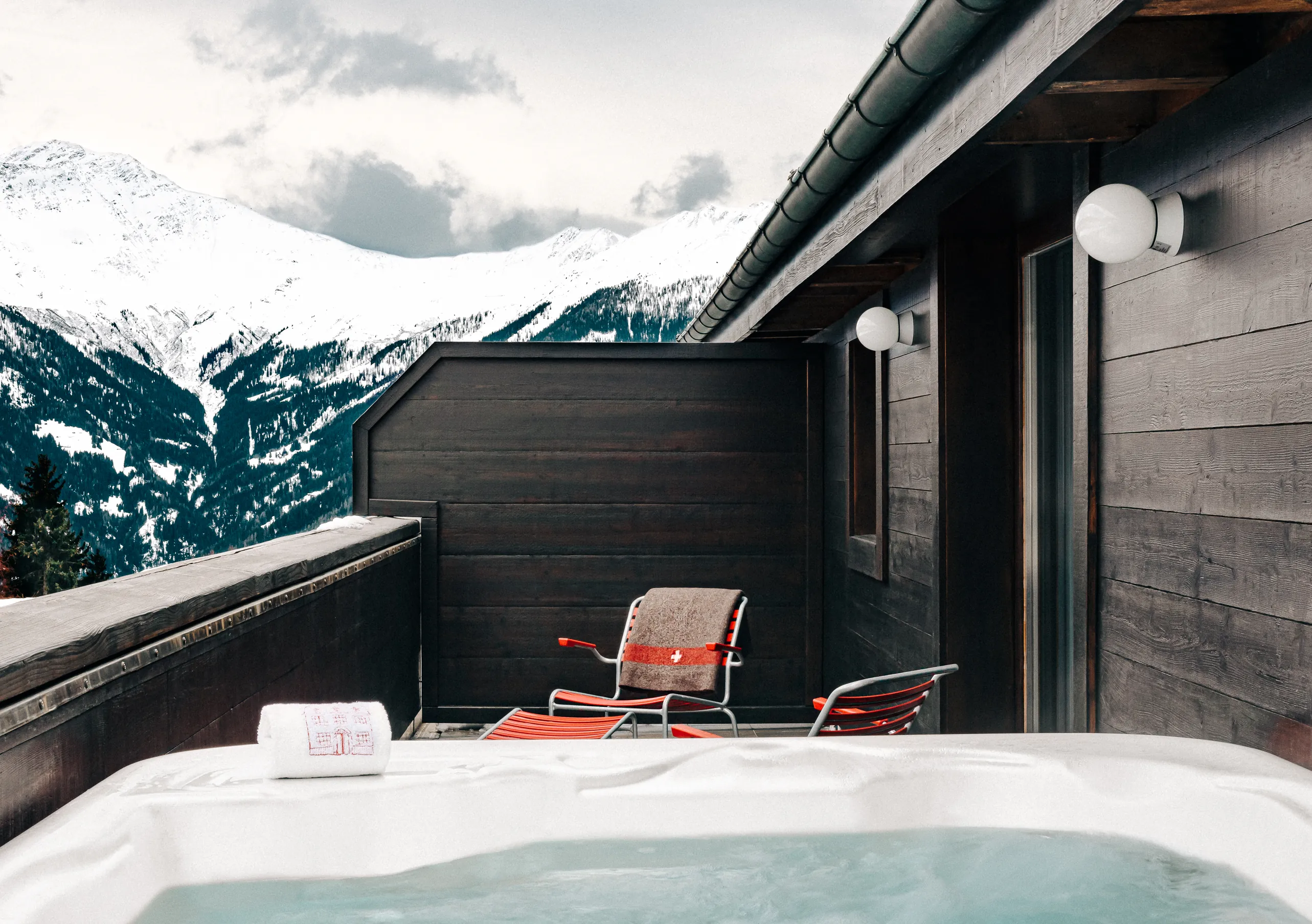 Private outdoor jacuzzi with a snowy mountain view in the Verbier Suite at Experimental Chalet Verbier, luxury ski and spa hotel in Verbier