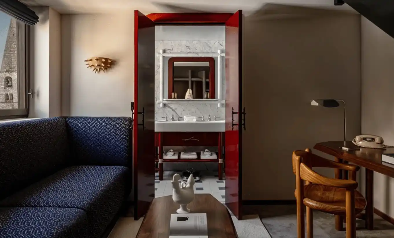 Open-plan room with a navy blue sofa, wooden desk and a red door in the Loft at Experimental Chalet Val d'Isère