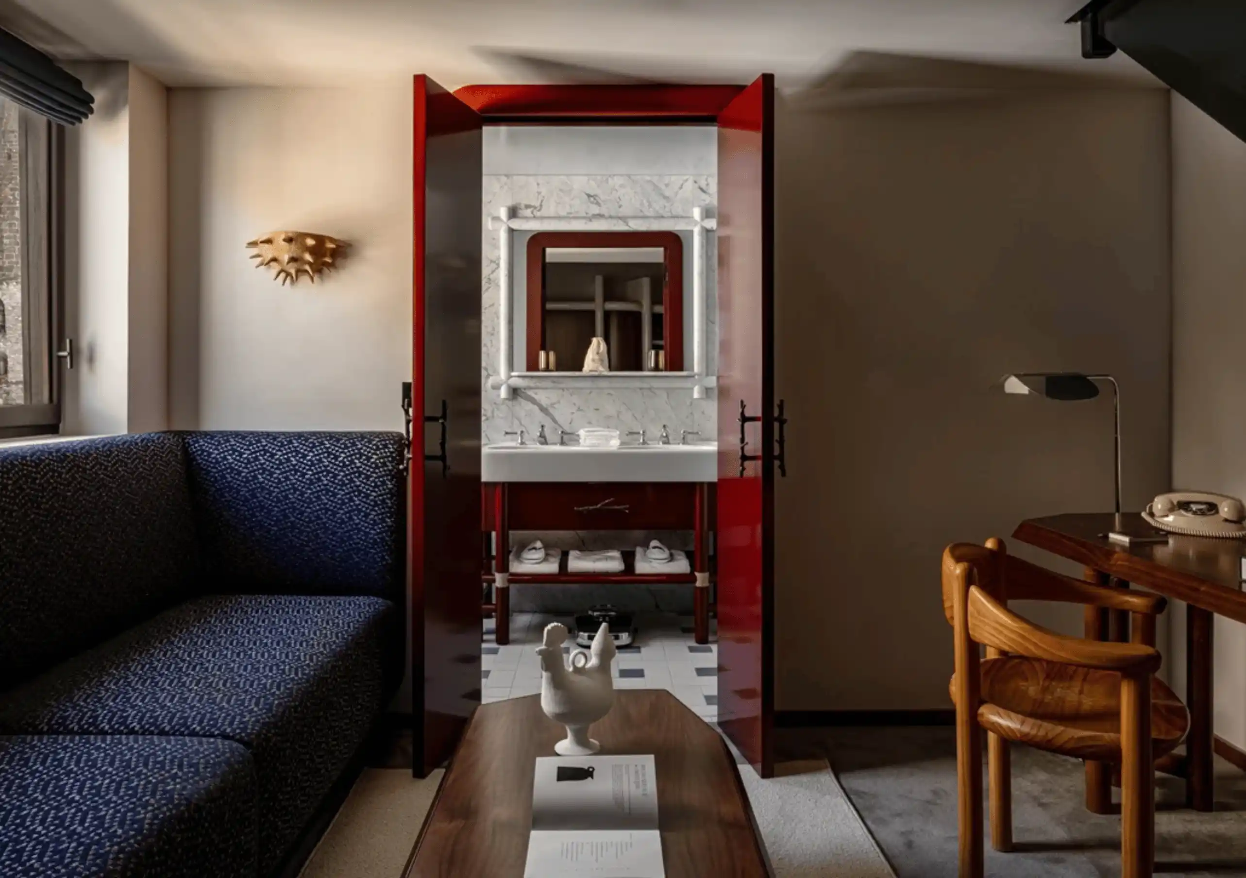 Open-plan room with a navy blue sofa, wooden desk and a red door in the Loft at Experimental Chalet Val d'Isère