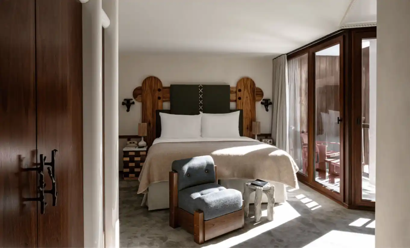 Chambre lumineuse avec grand lit blanc, armoire en bois et grandes fenêtres dans la Junior Suite Solaise de l'Experimental Chalet Val d'Isère