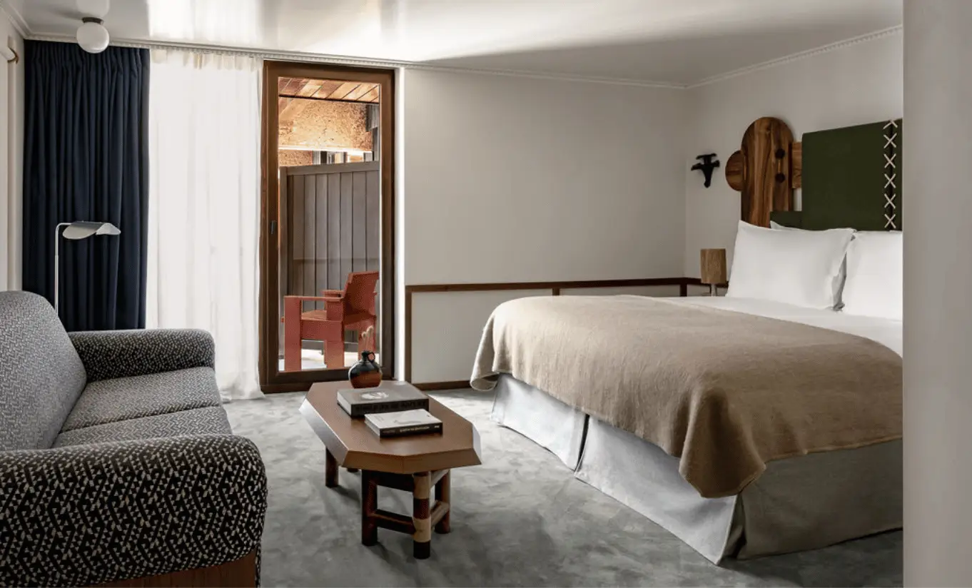 Chambre lumineuse avec deux lits simples, rideaux bleu marine et décor alpin en bois dans l'Olympique Deluxe de l'Experimental Chalet Val d'Isère