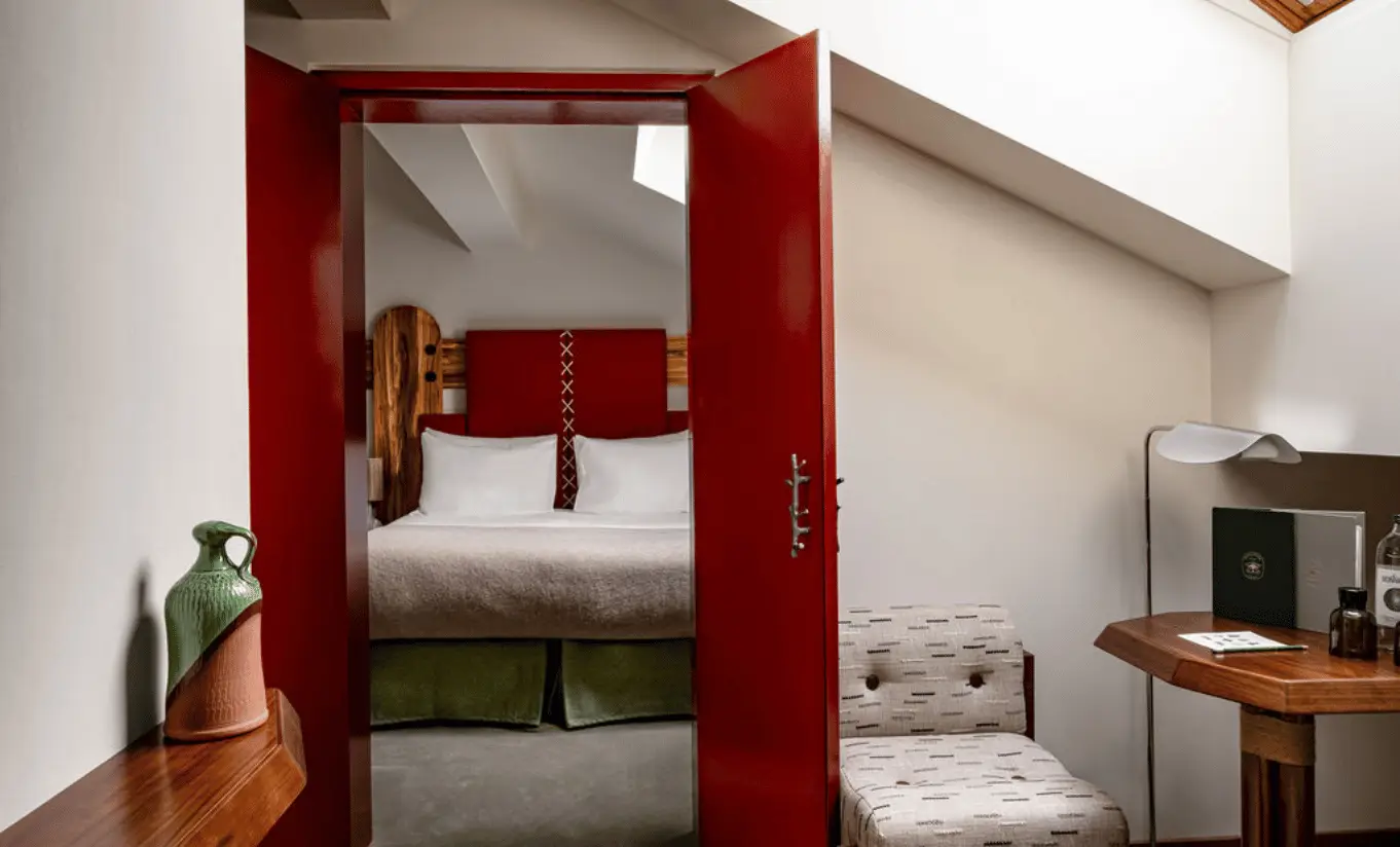 Compact room with a red door, green accents and a single bed in the Val d'Isère Under the Eaves at Experimental Chalet Val d'Isère
