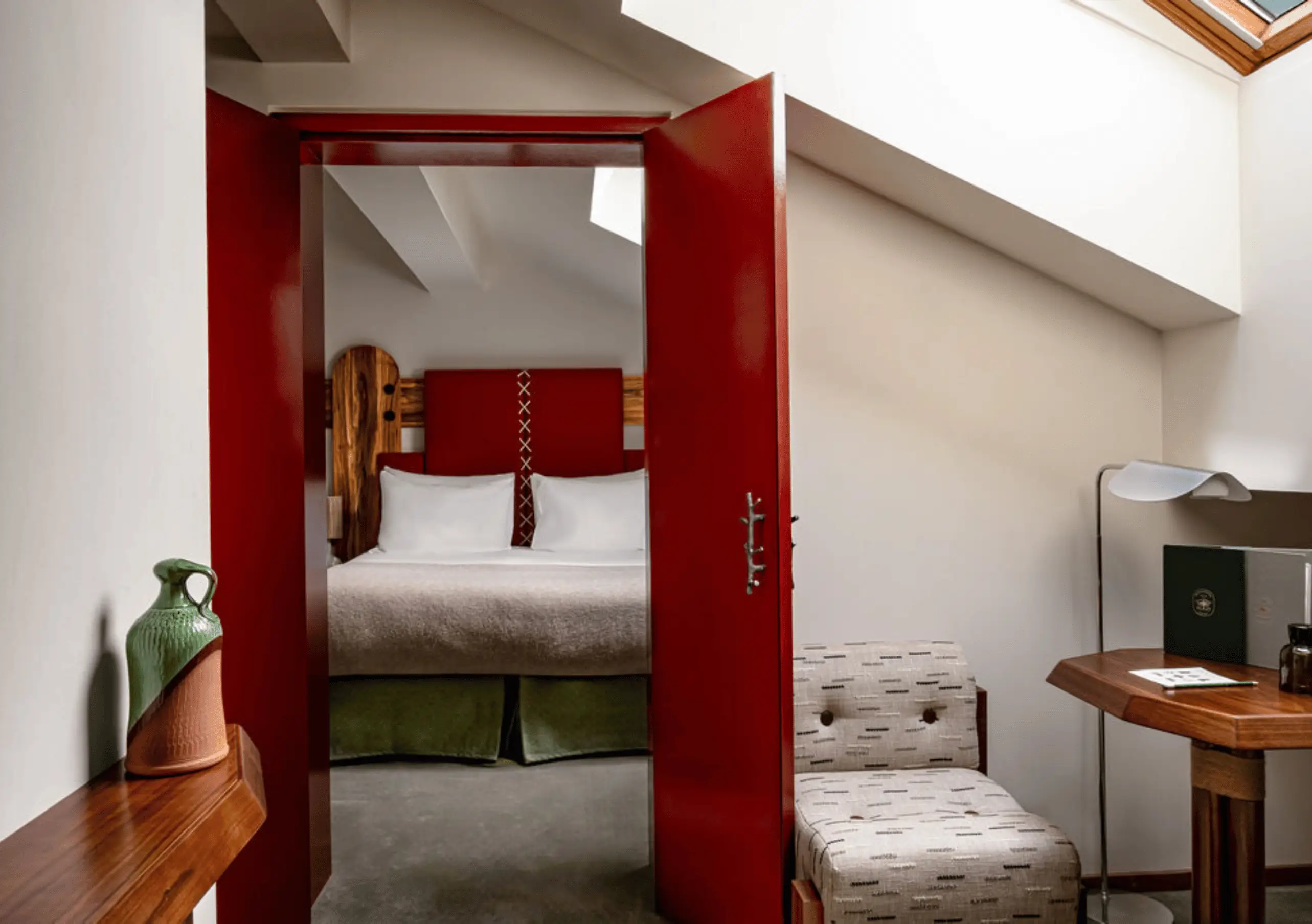 Compact room with a red door, green accents and a single bed in the Val d'Isère Under the Eaves at Experimental Chalet Val d'Isère