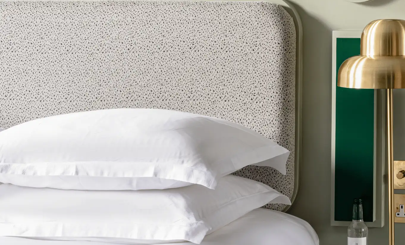 Détail d'oreillers blancs, tête de lit texturée et lampe de chevet dorée dans la Grand Saint Paul - Suite Junior de Henrietta Experimental, hôtel boutique à Covent Garden, Londres