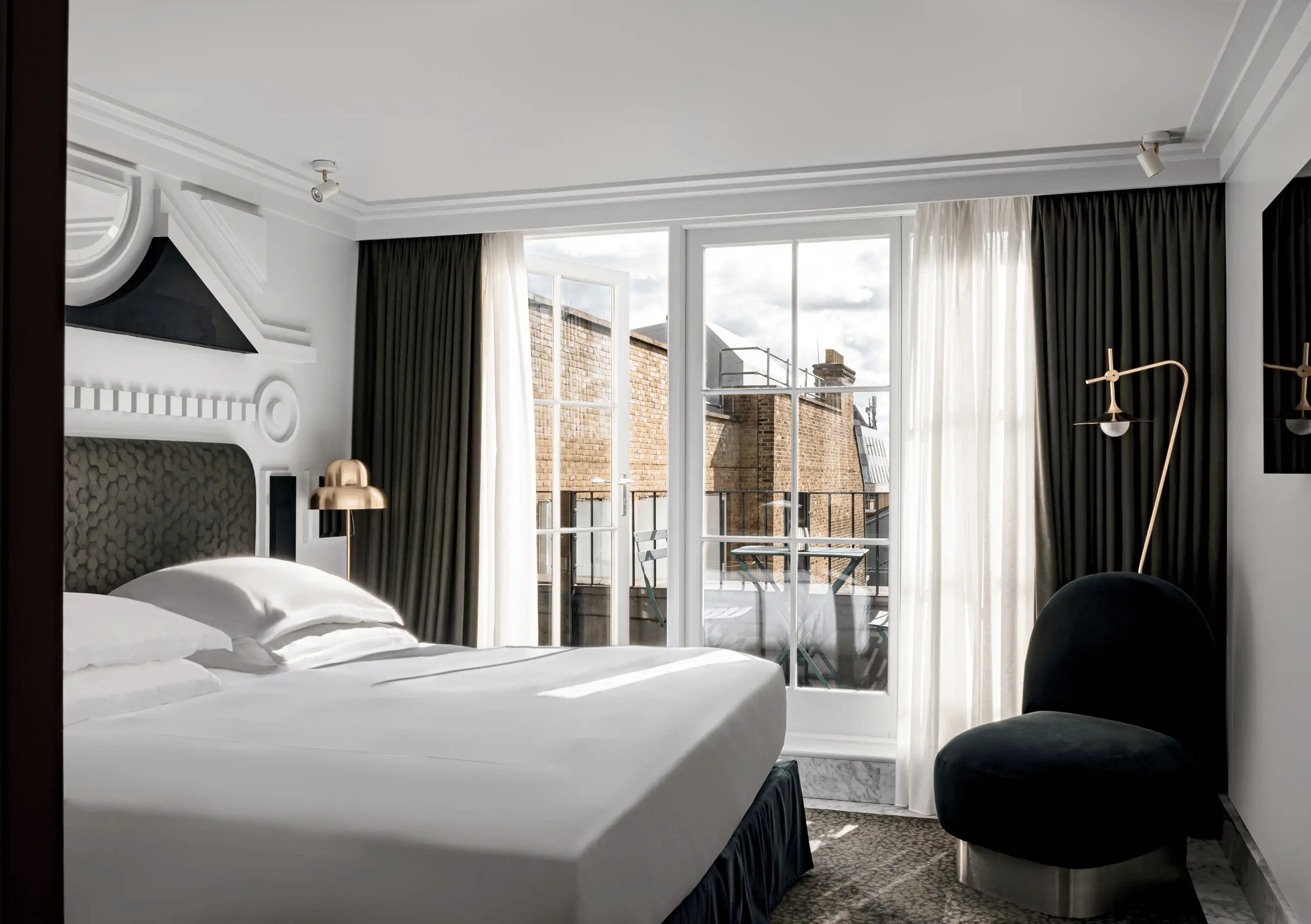 Experimental Group sophisticated hotel room with black and white décor, floor-length curtains and a private balcony overlooking Paris.