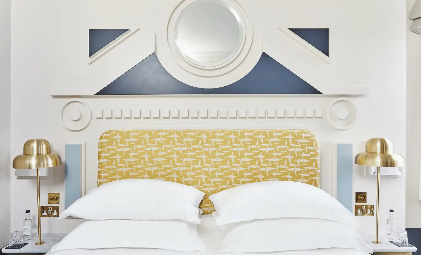 Bedroom with a white double bed, a gold floral headboard and ornate white mouldings in the Floral Superior Room at Henrietta Experimental, boutique hotel in Covent Garden, central London